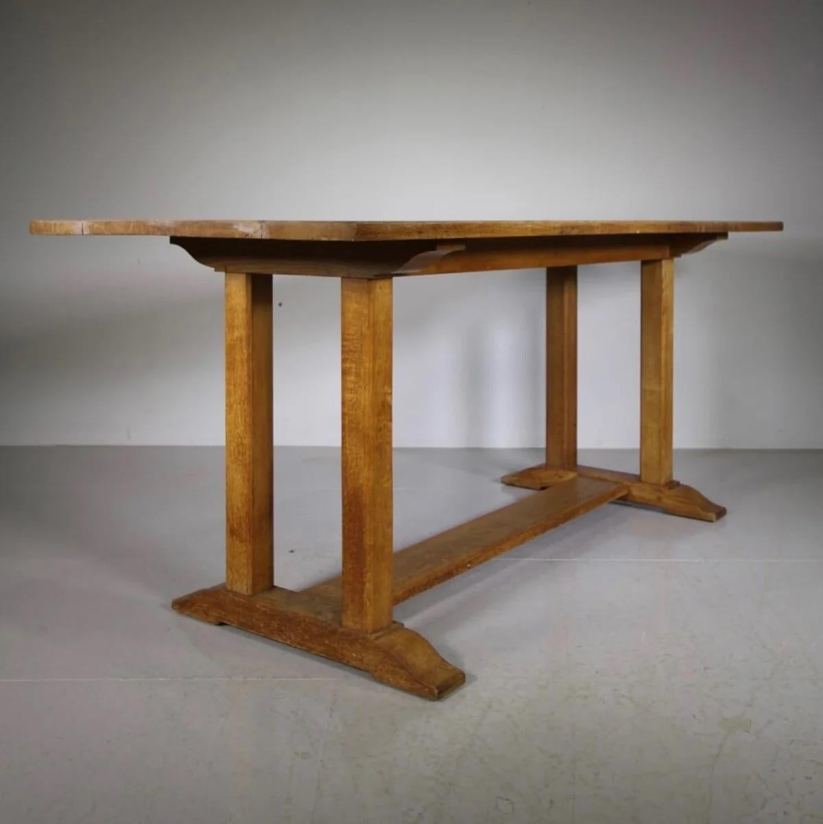 This substantial Heals of London solid oak refectory dining table, blends sturdy construction with timeless style. The design features twin square pillars at each end connected by a flat platform stretcher, providing both support and a distinct