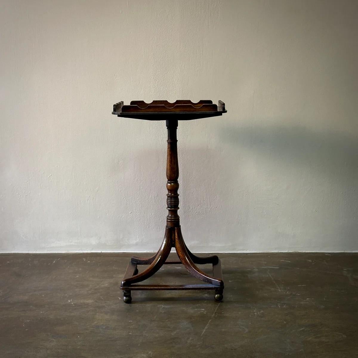 This late 19th-century English mahogany tilt-top table showcases exquisite craftsmanship with its carved gallery detailing and a slender, hand-carved base. The elegant design and functional versatility make it a charming choice for both traditional