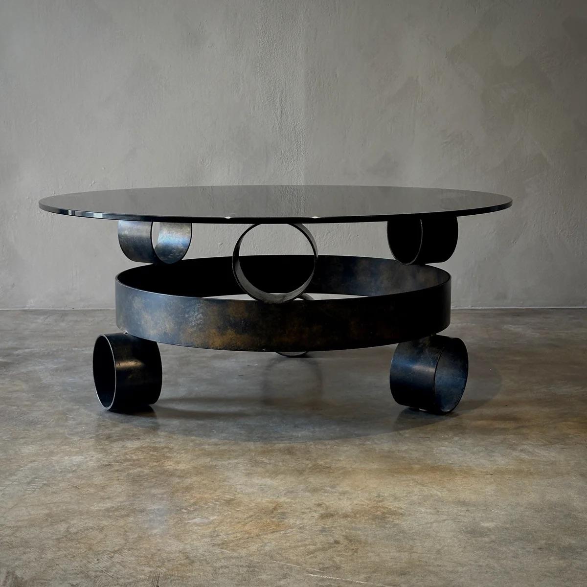Cette table basse belge brutaliste associe un fer forgé robuste à un plateau en verre fumé circulaire et élégant, incarnant une esthétique industrielle brute. Sa forme sculpturale et ses contrastes de texture en font une pièce maîtresse accrocheuse