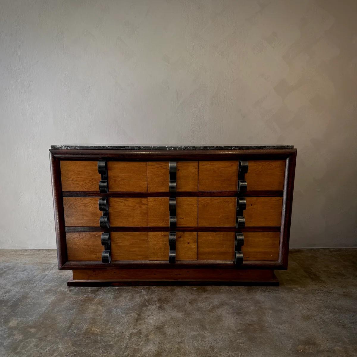 A striking example of mid-century French craftsmanship, this chest of drawers combines the warmth of natural wood with the bold contrast of dark iron handles. With a balance of organic materials and industrial details, this piece embodies the