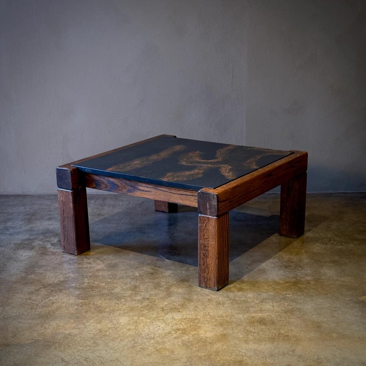 This faux slate top coffee table showcases a robust and rustic charm, blending a dark, textured tabletop with solid wooden legs for a sturdy, grounded look. The imitation slate surface provides a touch of nature-inspired aesthetic without the