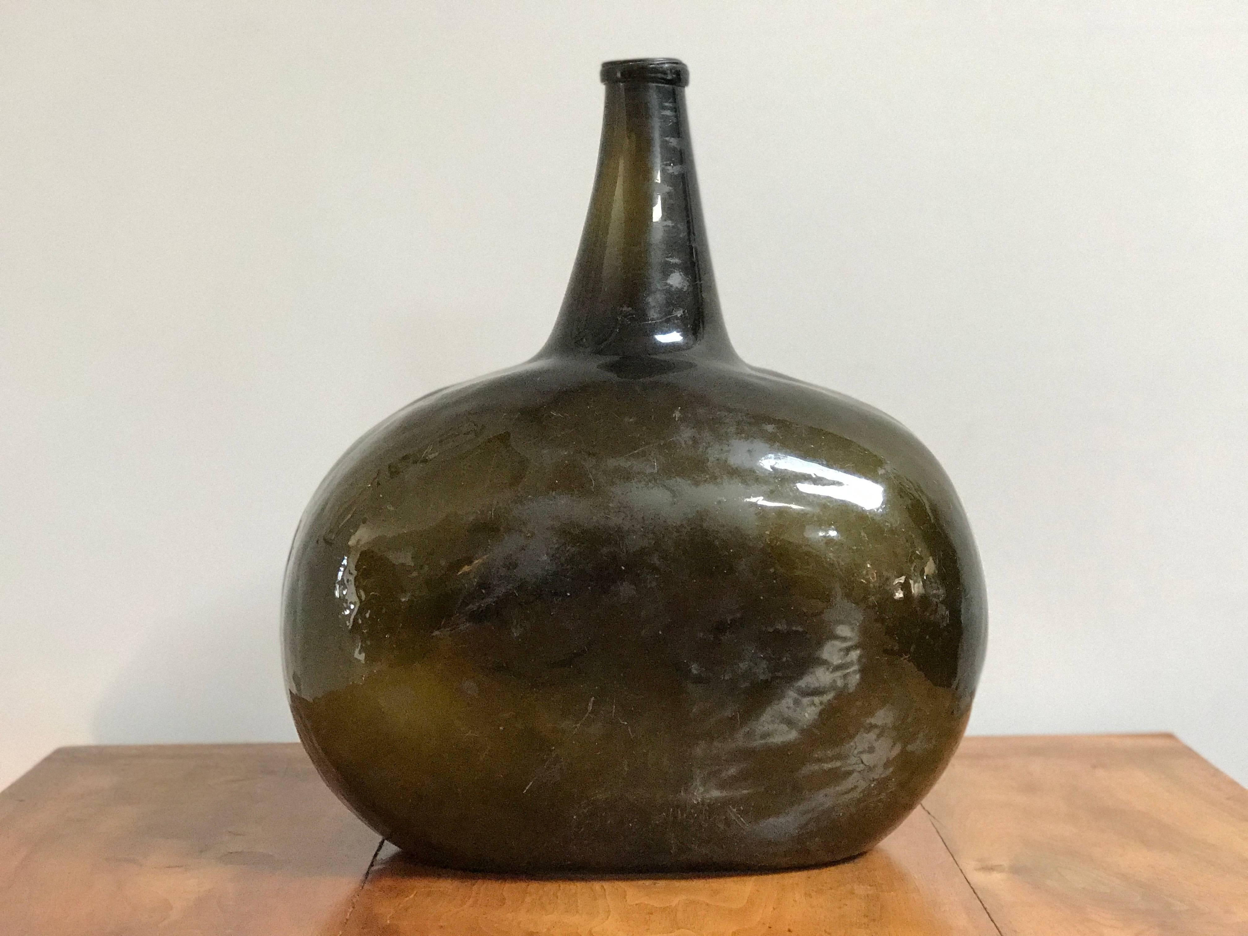 19th-century spherical blown-glass bottle from France. The color is an exceptionally rich olive hue. The rustic shape and texture give this bottle a French country charm. Could work as a decorative object in its own right, or as a vase. 

France,