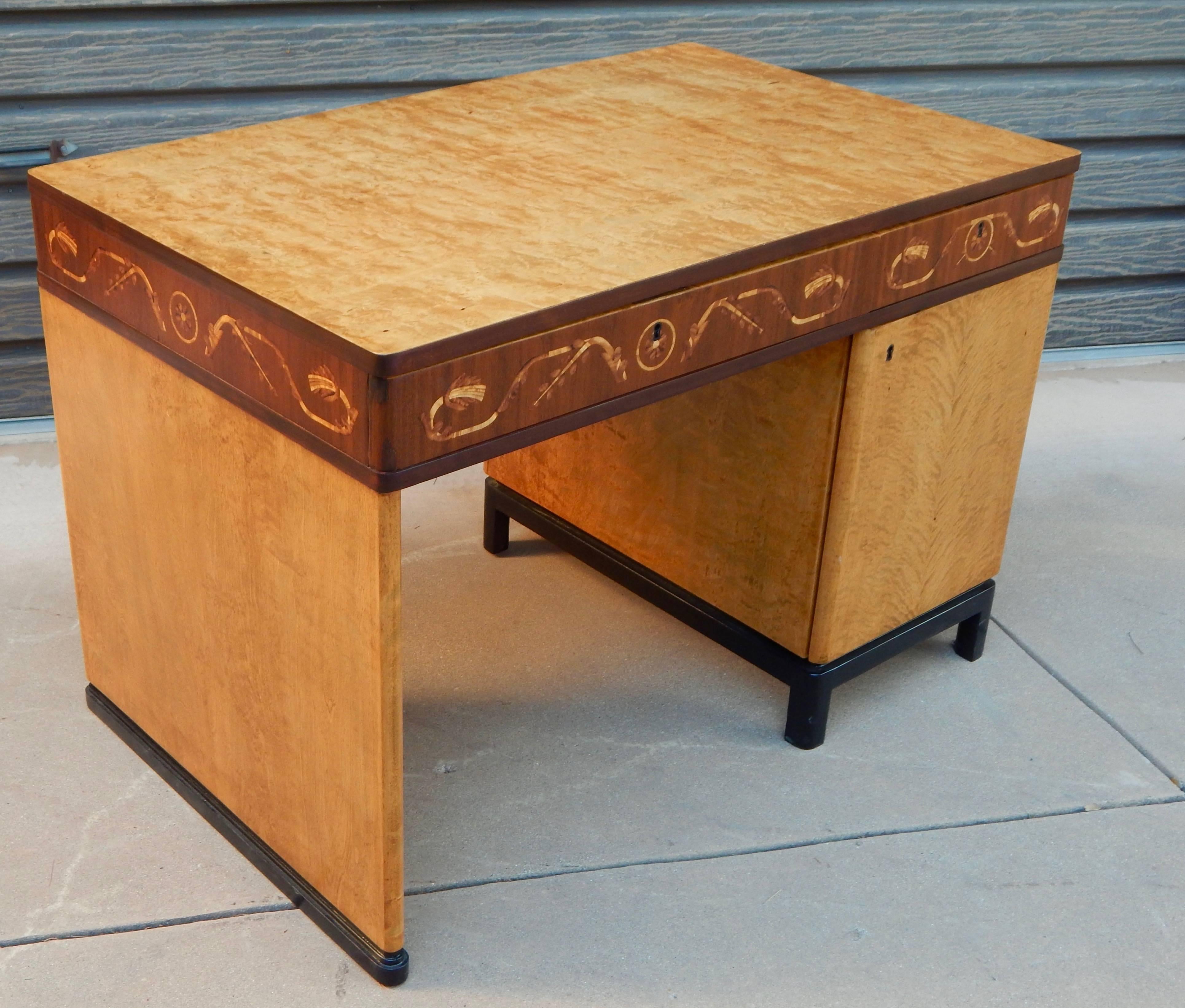 Swedish Art Deco inlaid desk made at Ferdinand Lundquist in Gothenburg, Sweden in the 1930s. Rendered in highly figured golden flame birchwood. Inlaid neoclassically inspired banding rendered in rosewood, Carpathian elm and birchwood. Ebonized birch