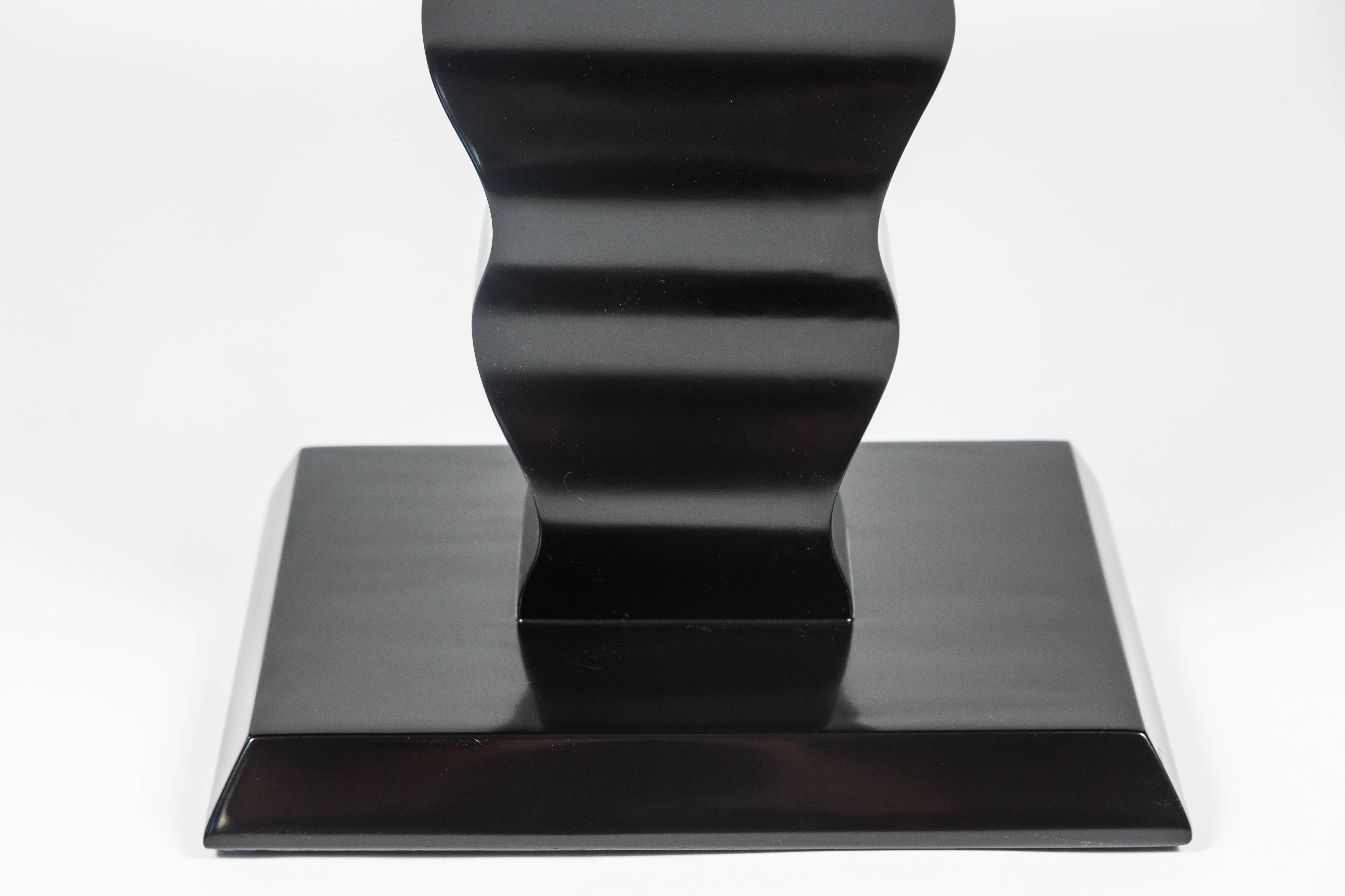 An elegant Art Deco occasional table by Karpen. Carved ebonized wood with a mahogany veneered top. Measures: 22 1/2 inches high. With makers label underneath.