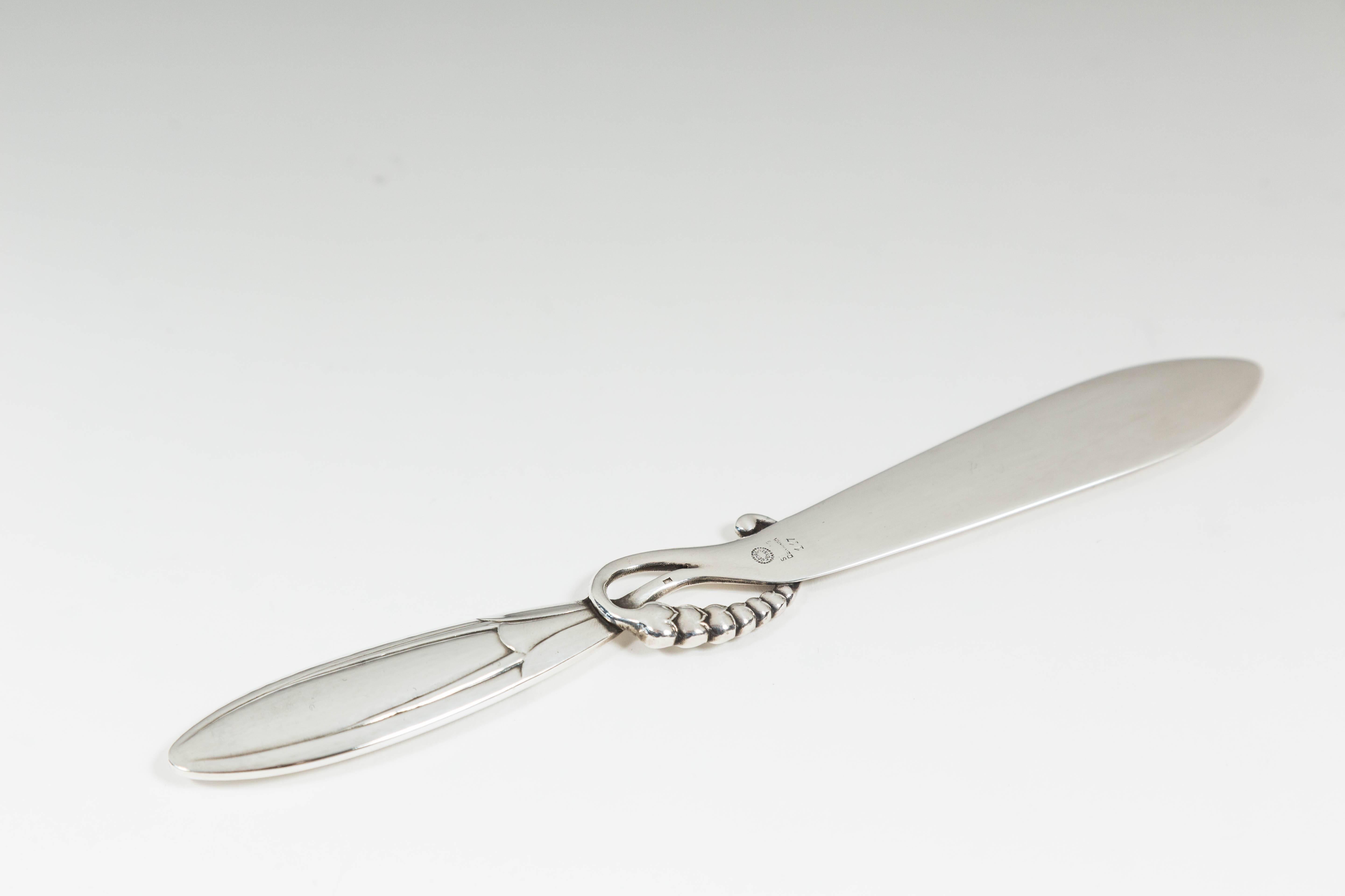 Enchanting letter opener by Danish manufacturer Georg Jensen. Sterling silver. With floral ornamentation about the handle. Bears Georg Jensen, Sterling Denmark silver marks on the blade. Model 117. Measures: 6 1/2 inches long. Jensen Hallmark dates
