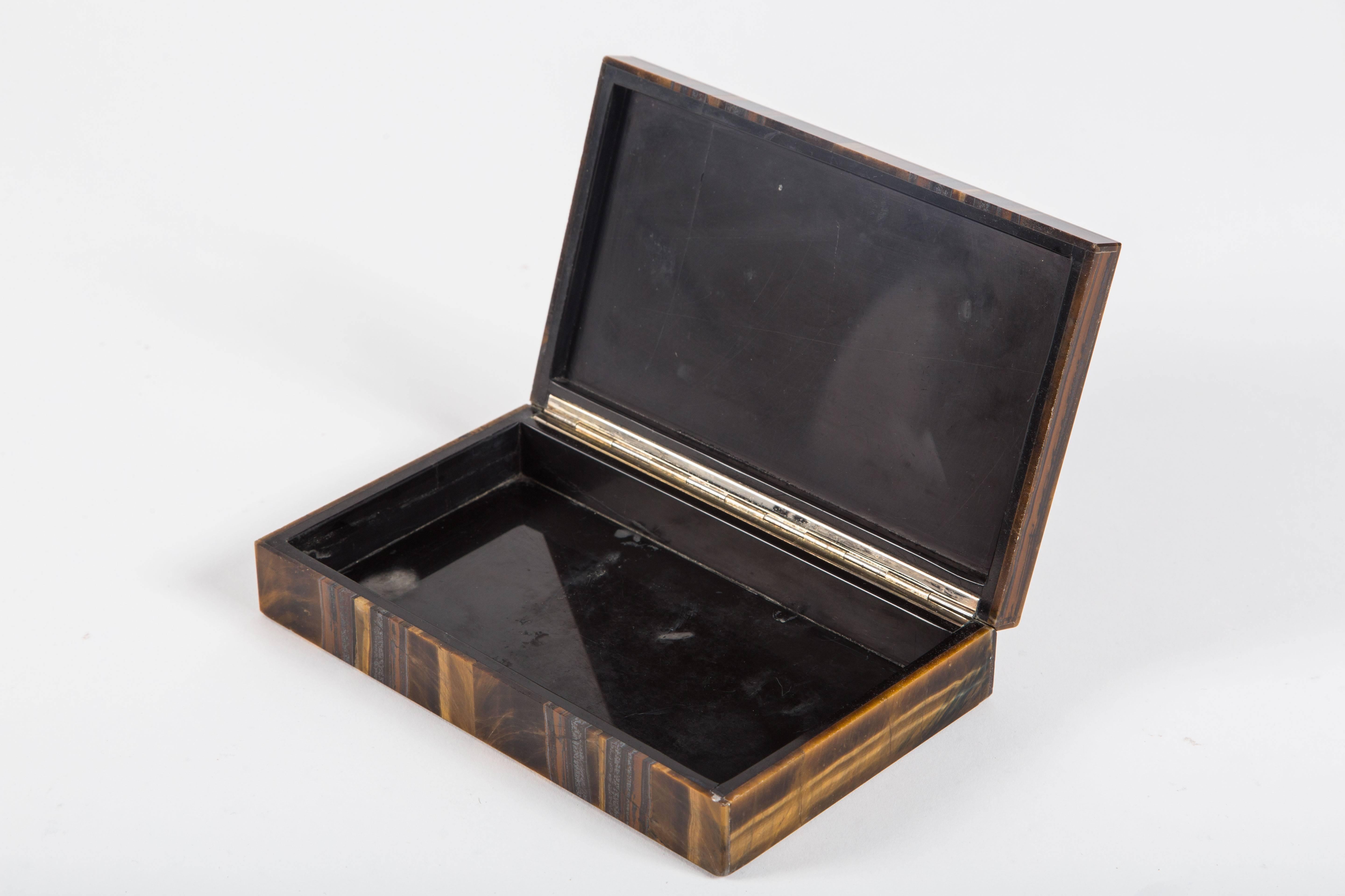 Fabulous hinged box veneered in beautiful tiger's eye. Italian made with black onyx interior. A made-in-Italy label remains beneath the box.

  