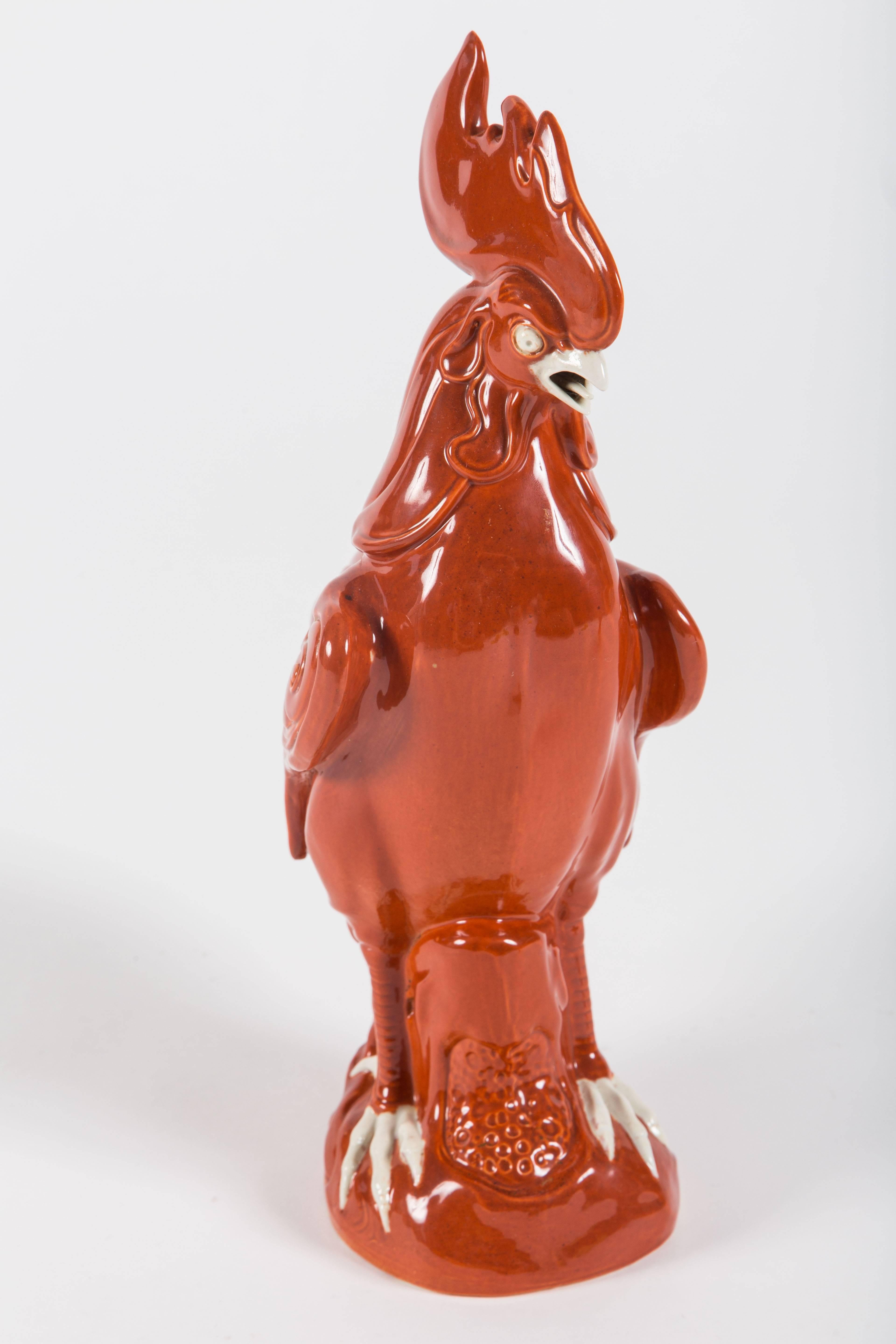 A striking pair of Chinese export porcelain roosters. Wonderfully detailed with feathers evoking flames, featuring a bright red and orange glazed finish, the pair is in excellent condition. Unique and original design.

Measures: 14 inches high.