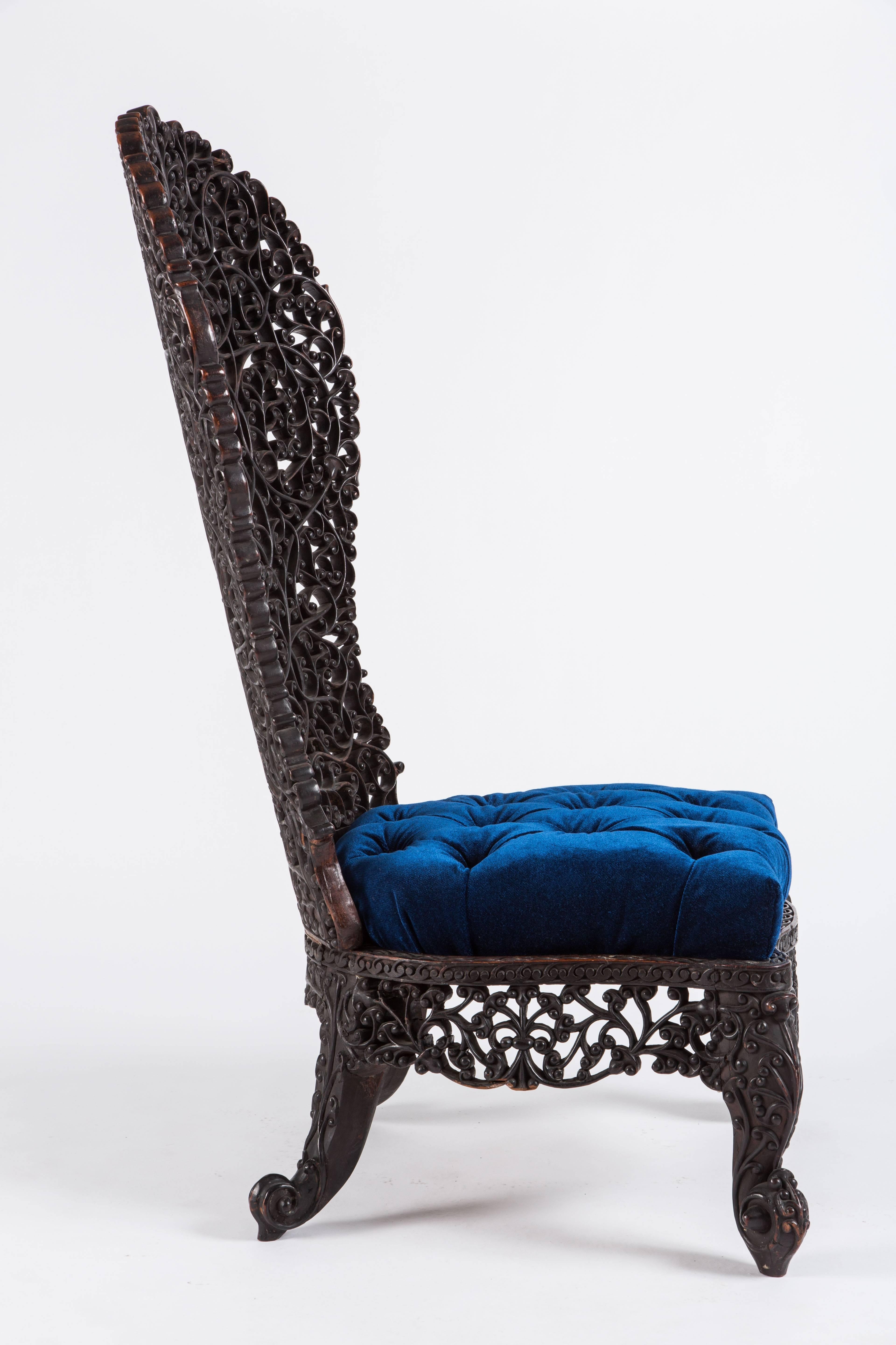 Fantastic Anglo-Indian high backed chair. Intricately carved throughout with leaf motif, with a newly upholstered tufted blue velvet seat. The seat measures 17 inches high.

           