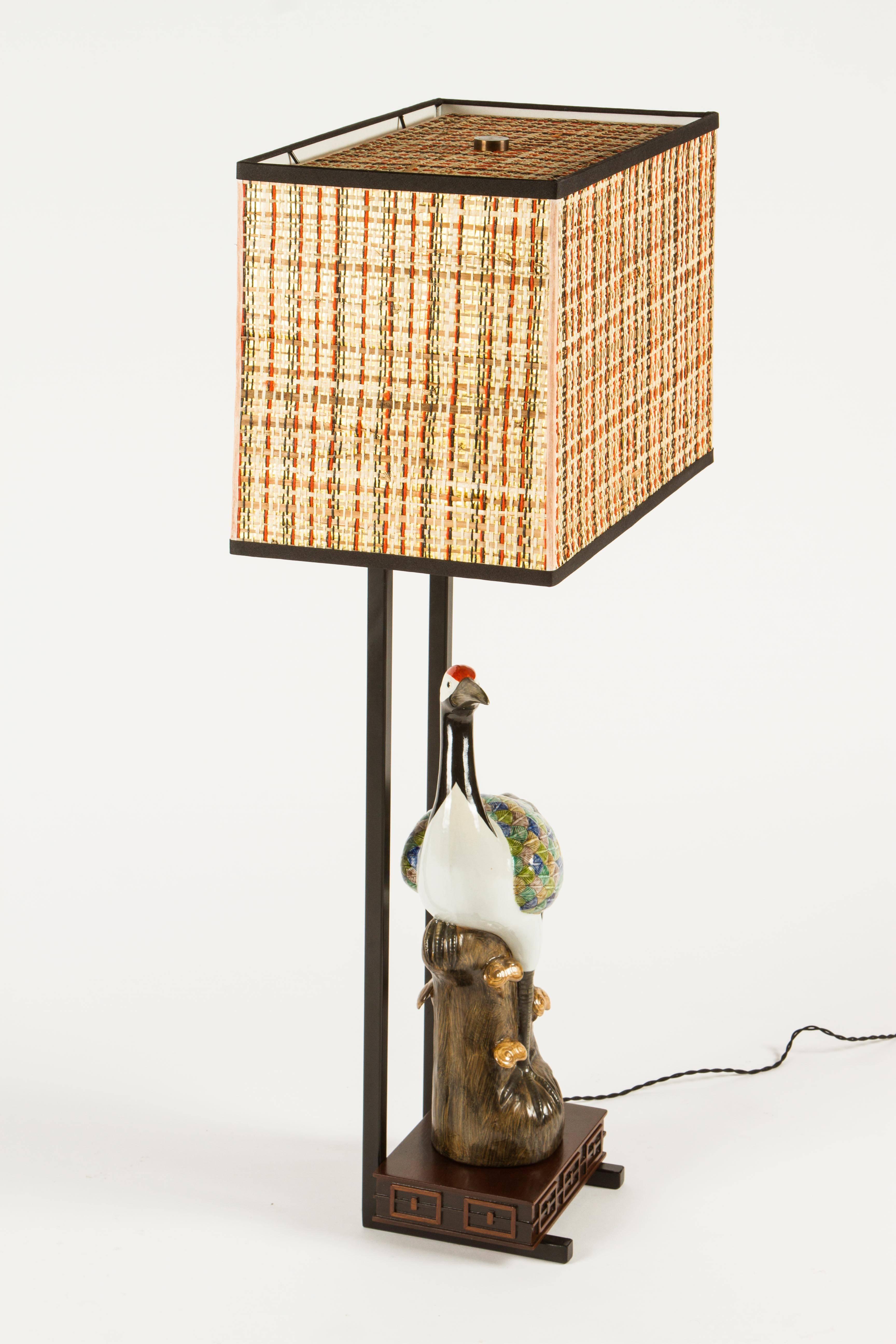 Wonderful armature table lamps by William Haines featuring Chinese ceramic egrets. The lamp is a highly polished dark brown walnut with a black metal armature. The egrets are not original to the lamp but quite often the figures have been replaced on