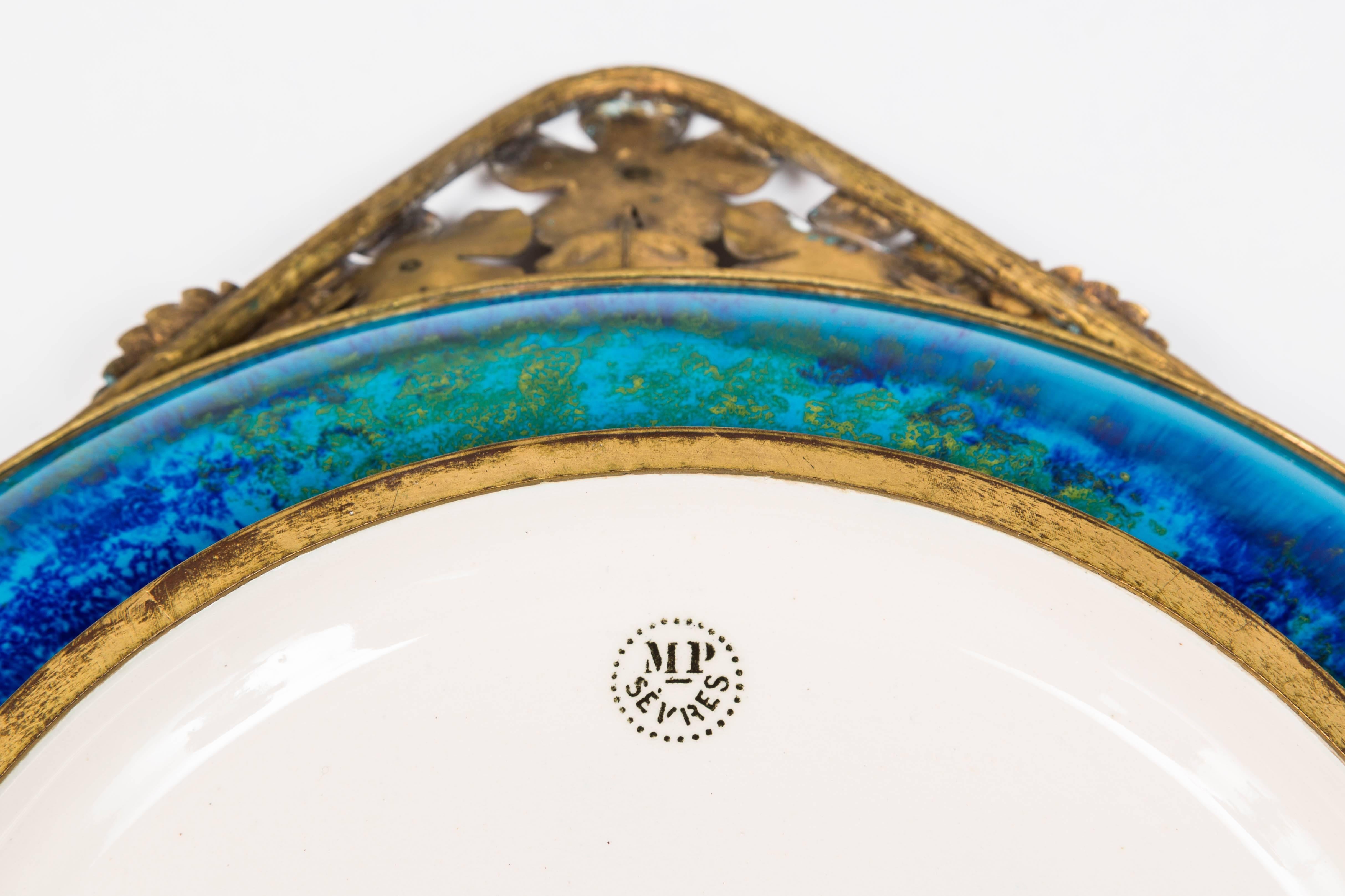 This wonderful and stylish platter designed by Paul Millet exhibits the Classic dappled glaze from this factory. The gilt metal features stylized flowers and foliage. Executed in the Art Deco style this is a wonderful addition to any interior.
 