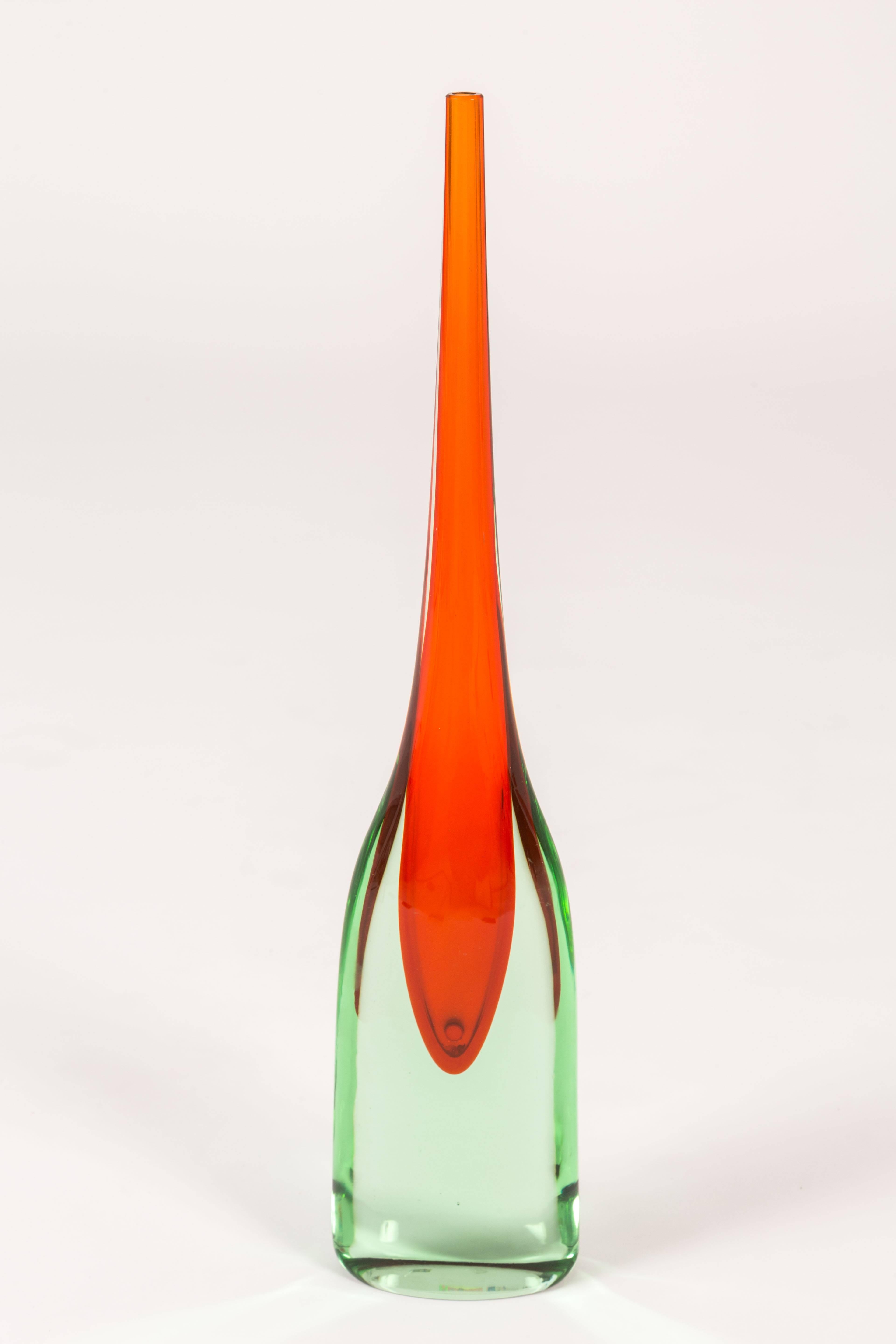 A tall and striking Murano glass vessel with an elongated neck. The glass is a pale green with orange interior.