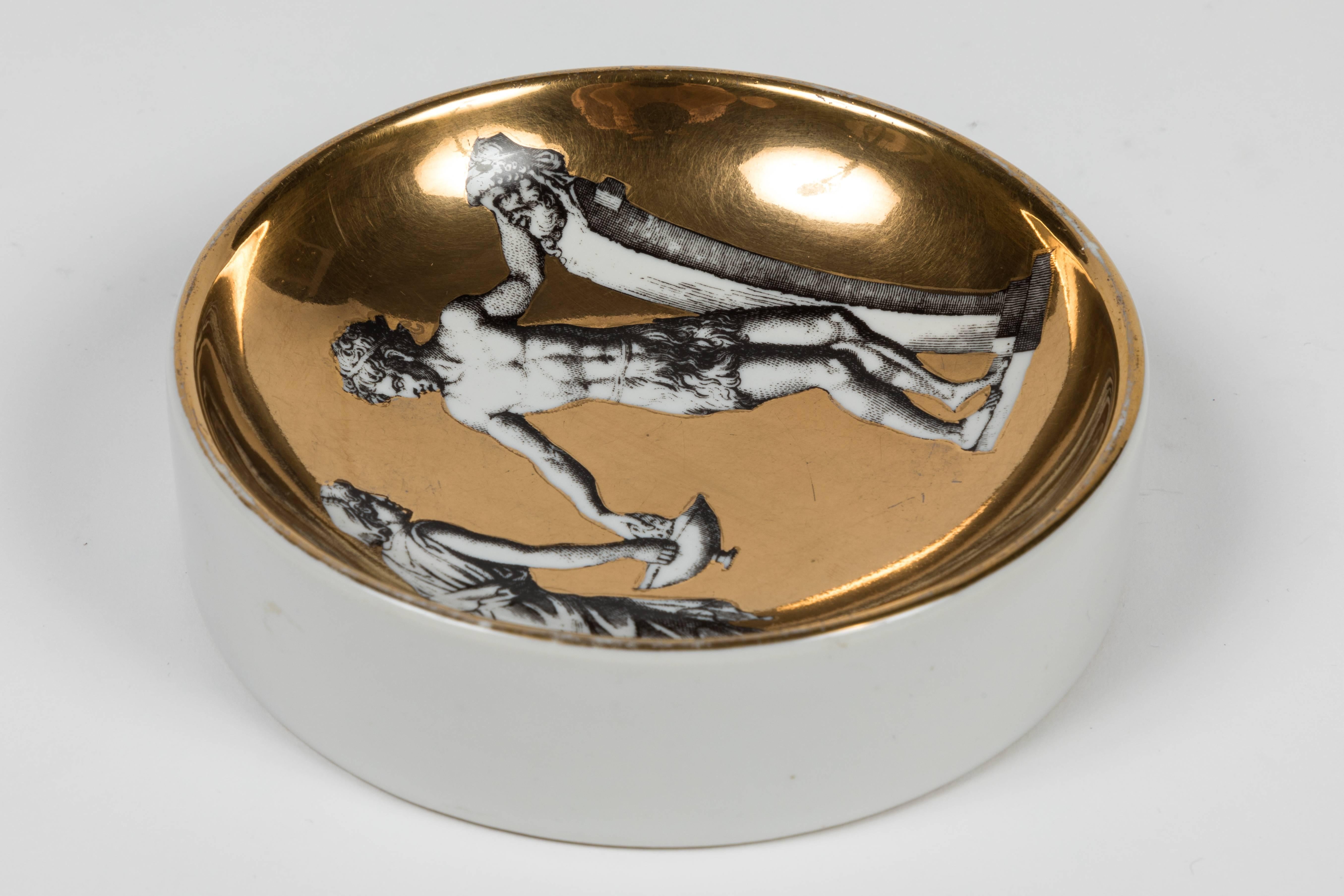 Vintage Fornasetti porcelain dish depicting two Roman figures. Could be used as a jewelry catch-all dish. A combination of gold glaze and black and white figures makes for a striking design.
Signed on the back.
Made in Italy.