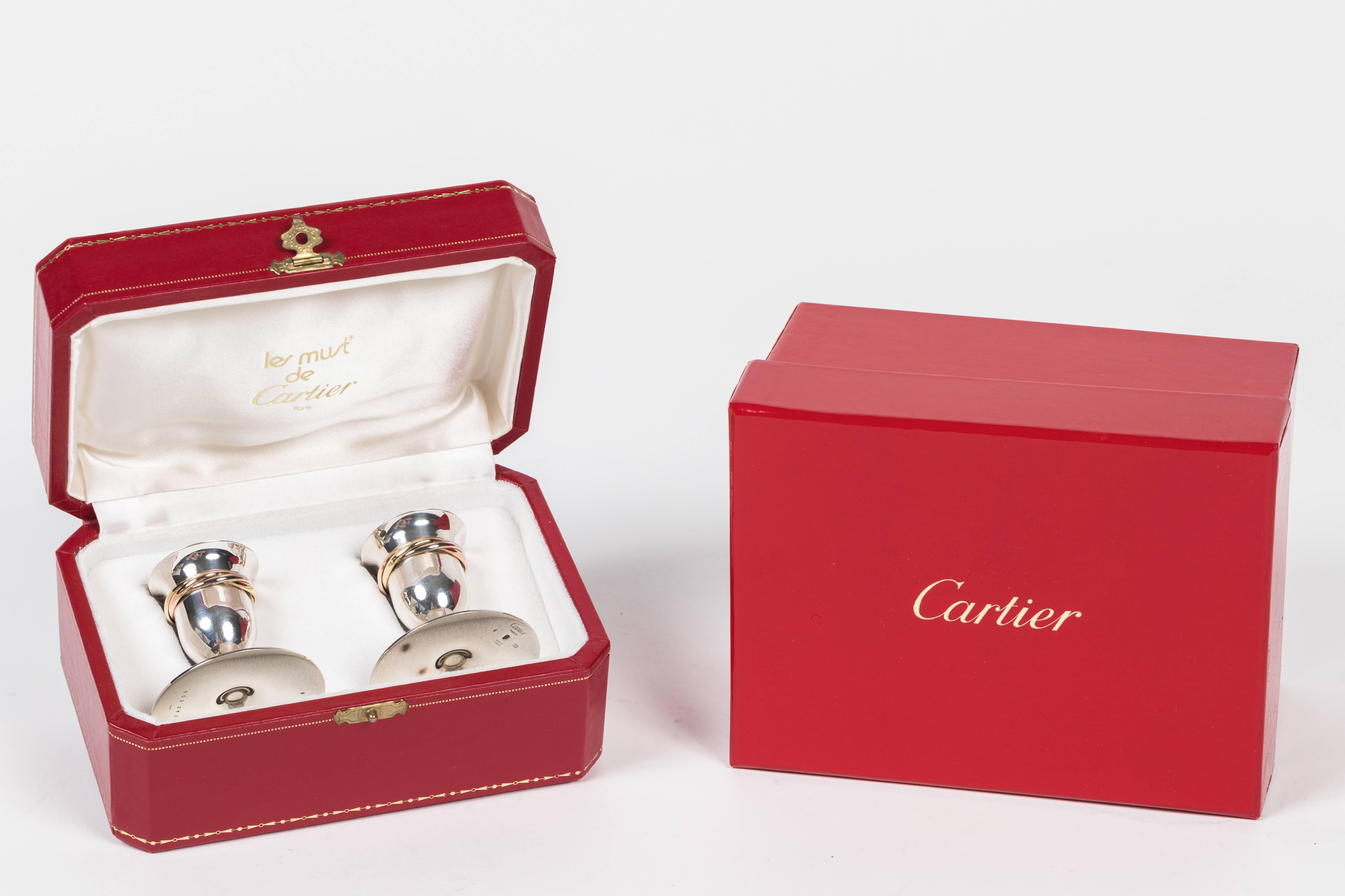 Wonderful pair of candleholders in sterling silver featuring the addition of tri-color rolling rings to each holder. We have both the original presentation box as well as the red Cartier outer gift box. Ready for holiday gift giving!
   