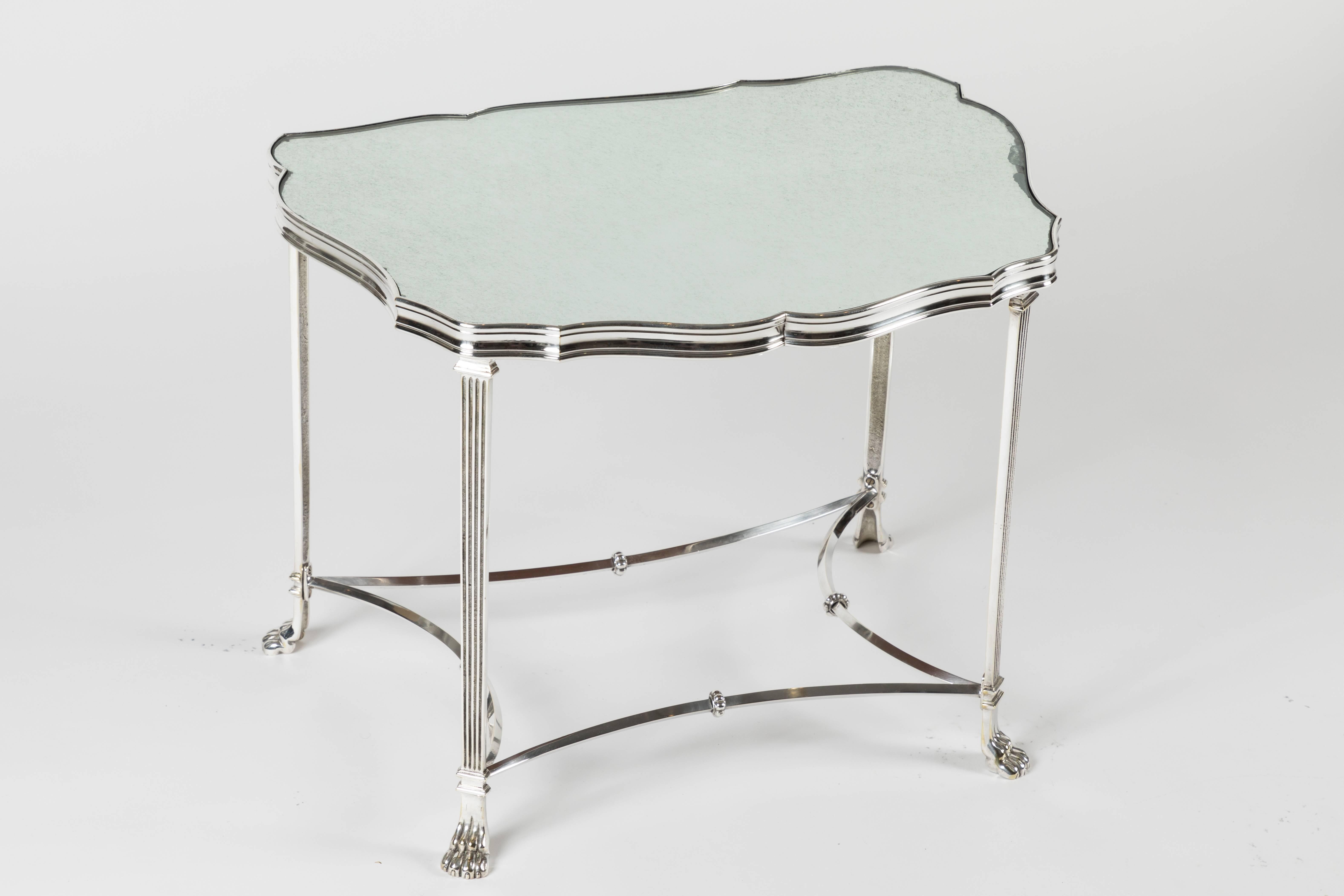 A beautiful pair of side tables with frames that terminate in claw feet and are finished in silver plate. Very reminiscent of Maison Jansen, the unusual shape is mirrored in the opposite table as they are a matched pair. The tables have 