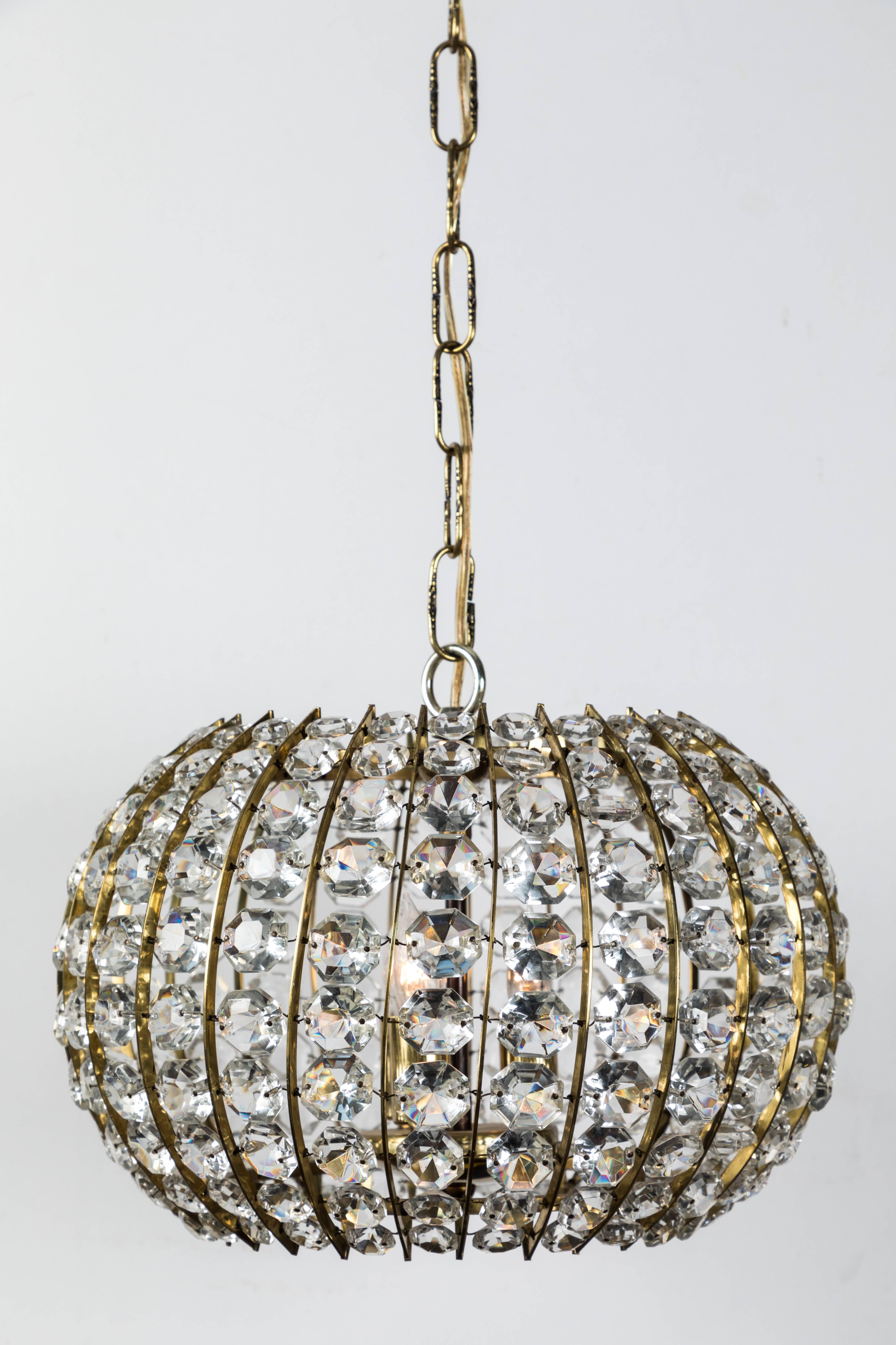 Our glamorous crystal and brass pendant fixture is a delight be behold. This faceted work of art features graduated crystals and has been re-wired to modern standards. 

Shape: oblate spheroid with open top and bottom.