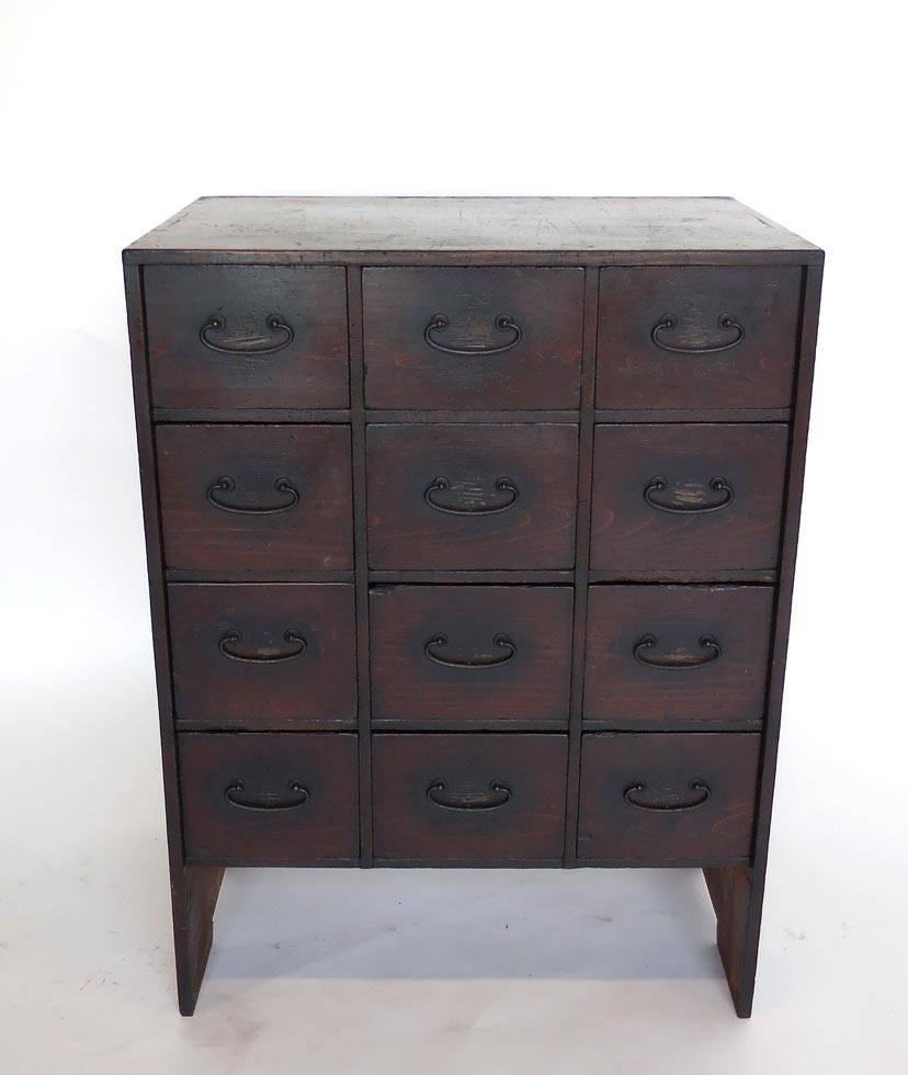 19th century Japanese shop chest with 12 drawers. All original. Petite size. Unusual. Hinoki wood, bamboo nails with had wrought iron. Sturdy and functional. Old natural patina.