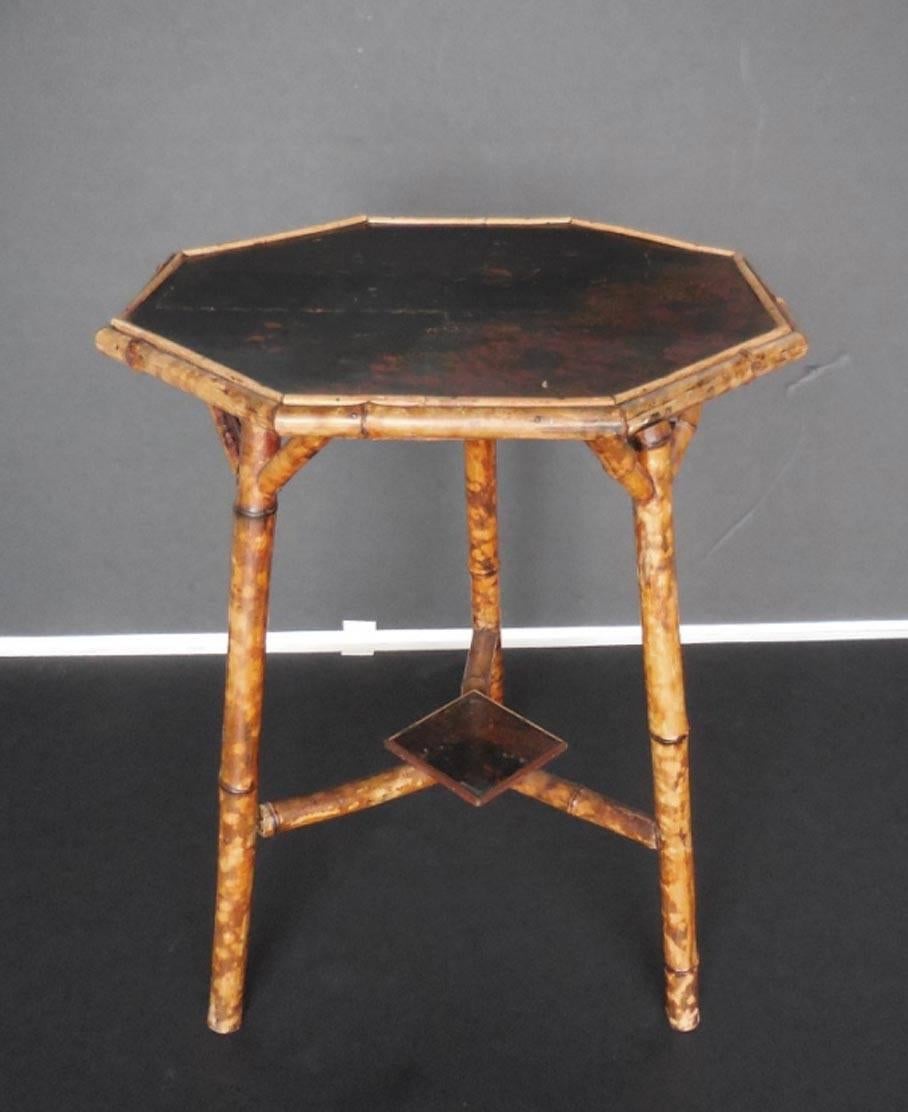 Painted in blacks and reds and gold, this table is a Classic. Enamel is a bit chipped in the middle but the table is stabile and totally functional. Perfectly proportioned. Small shelf across the bottom.