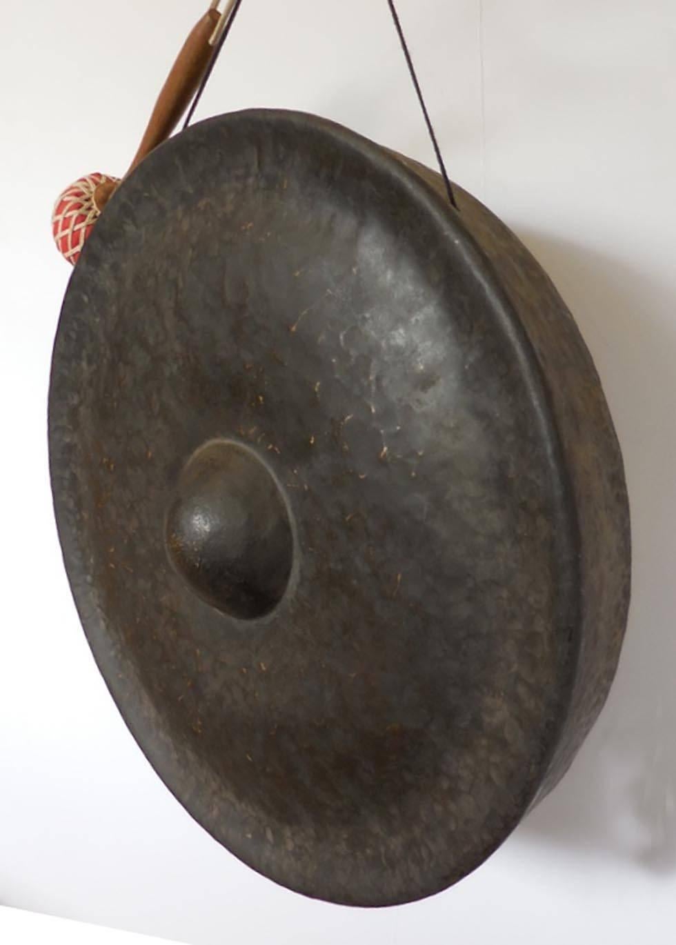 Hand-hammered bronze gong, original dark patina. Red padded striker. Deep baritone sound.