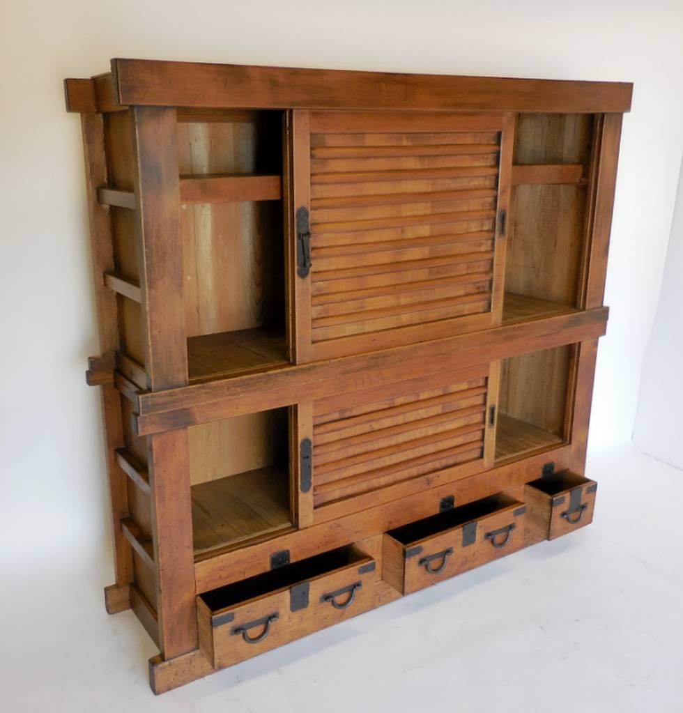 19th century Japanese tansu/dansu cabinet consisting of two separate pieces stacked on each other. Upper half has a inside shelf space and a pair of sliding doors that lock. Lower cabinet a pair sliding doors and three drawers. Original hardware,