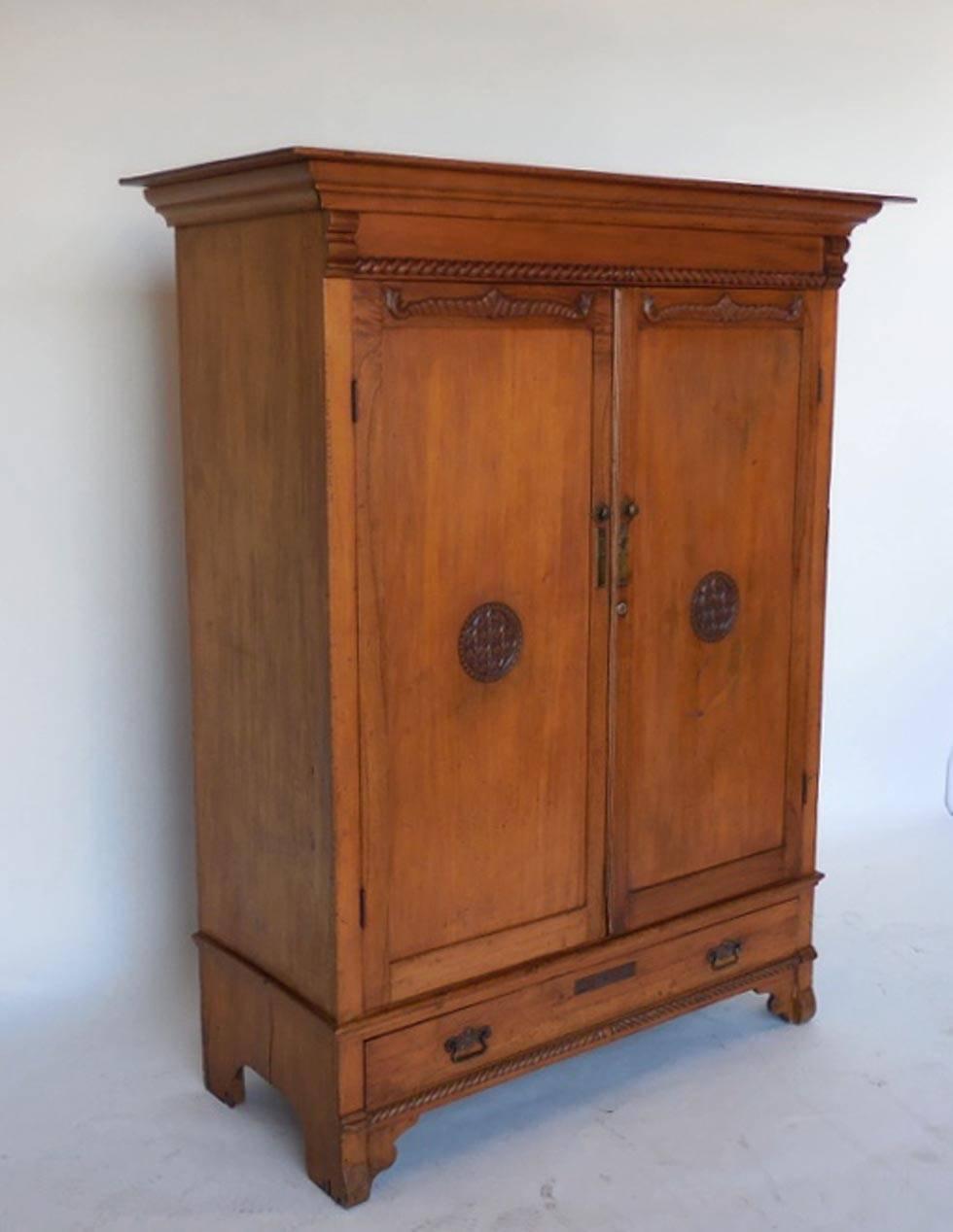 Cedro (tropical hardwood) cabinet or wardrobe with Asian inspired carved designs on doors. Interior features four shelves and two drawers. Shows normal signs of wear considering its age but is fully functional and sturdy. Doors work well. Inside of