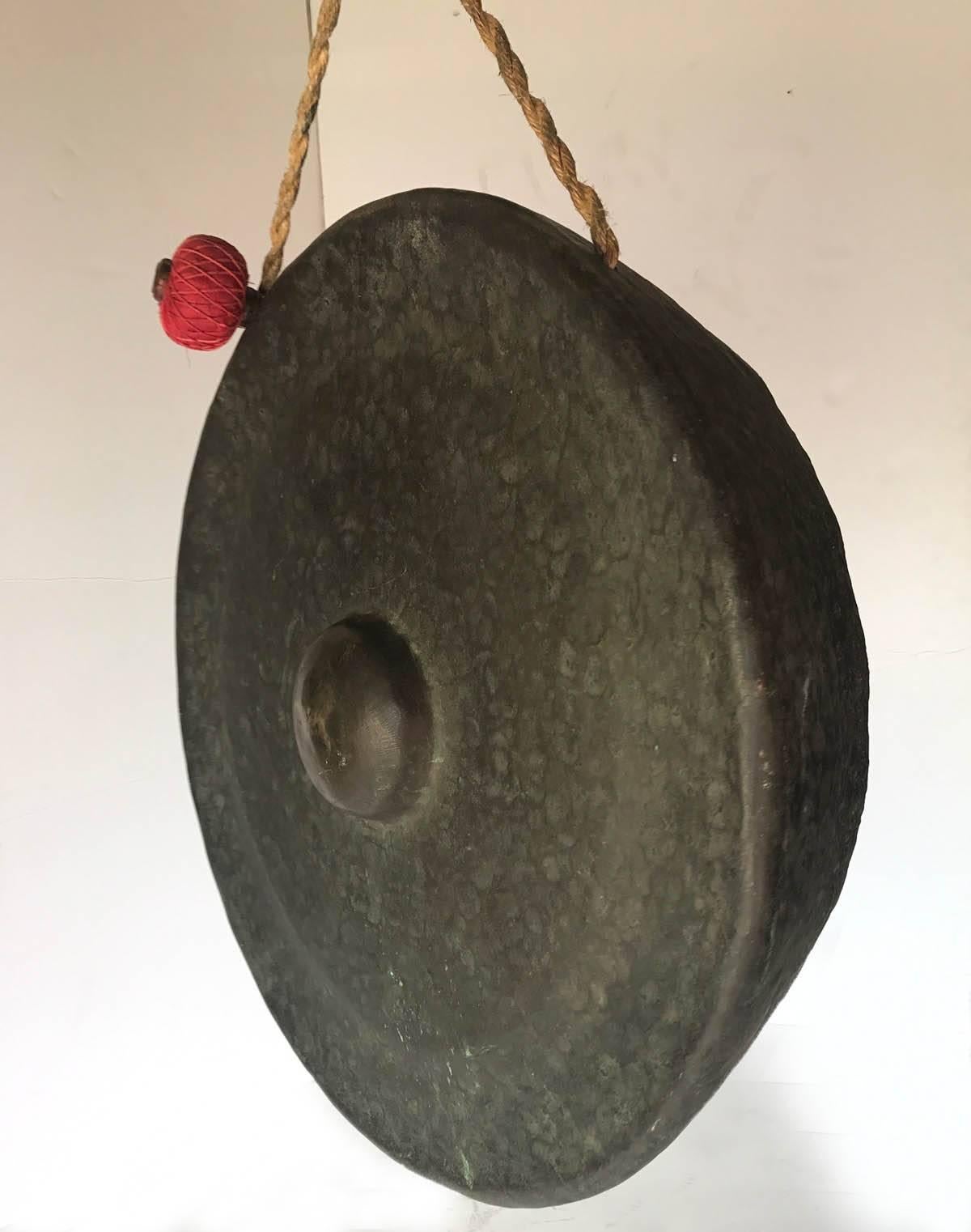20th century Indonesian hand-forged solid bronze gong with red striker. Deep resonant sound. Bronze patina and large size makes this piece a Classic example of simple elegant, functional design. It is 30