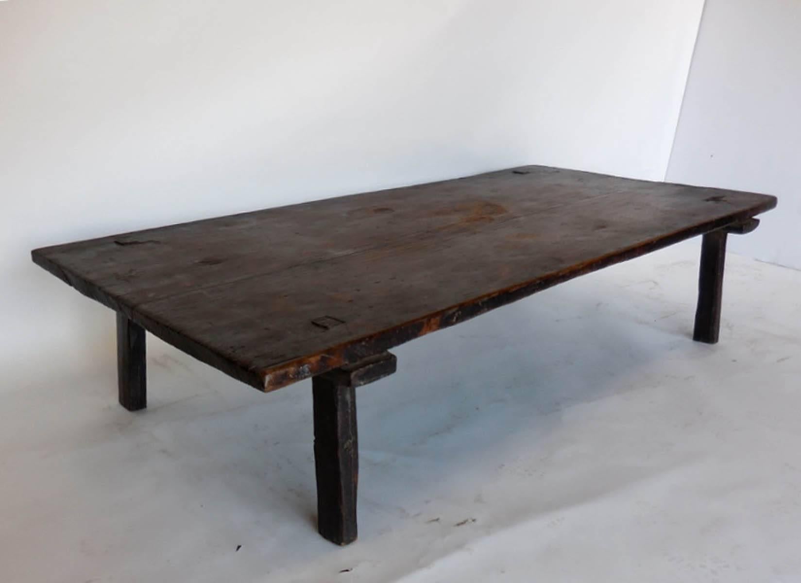 One wide board top, all original coffee table, (originally a bed). Straight legs, mortise and tenon construction. Some candle burns, original dark patina, which occurred naturally since it existed in an indigenous home with open fires and smoke.