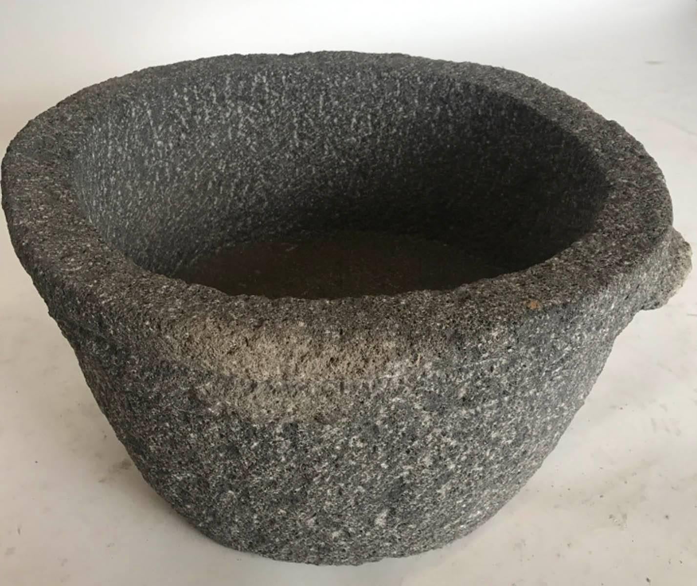 Hand-carved grey toned volcanic rock trough. Interior depth is 17 inches. Carved round double rim and small handles. In good condition.