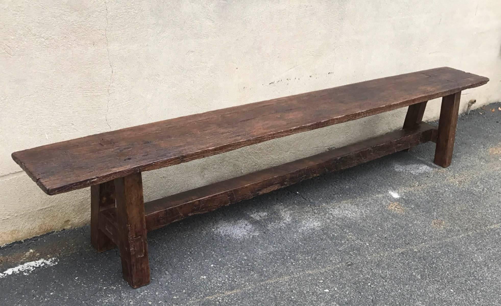 Very old wooden bench. Parts of the base has been replaced over the years, which is normal for this type of piece. Old repairs. Mortise and tenon construction, straight Primitive legs. Natural worn patina.