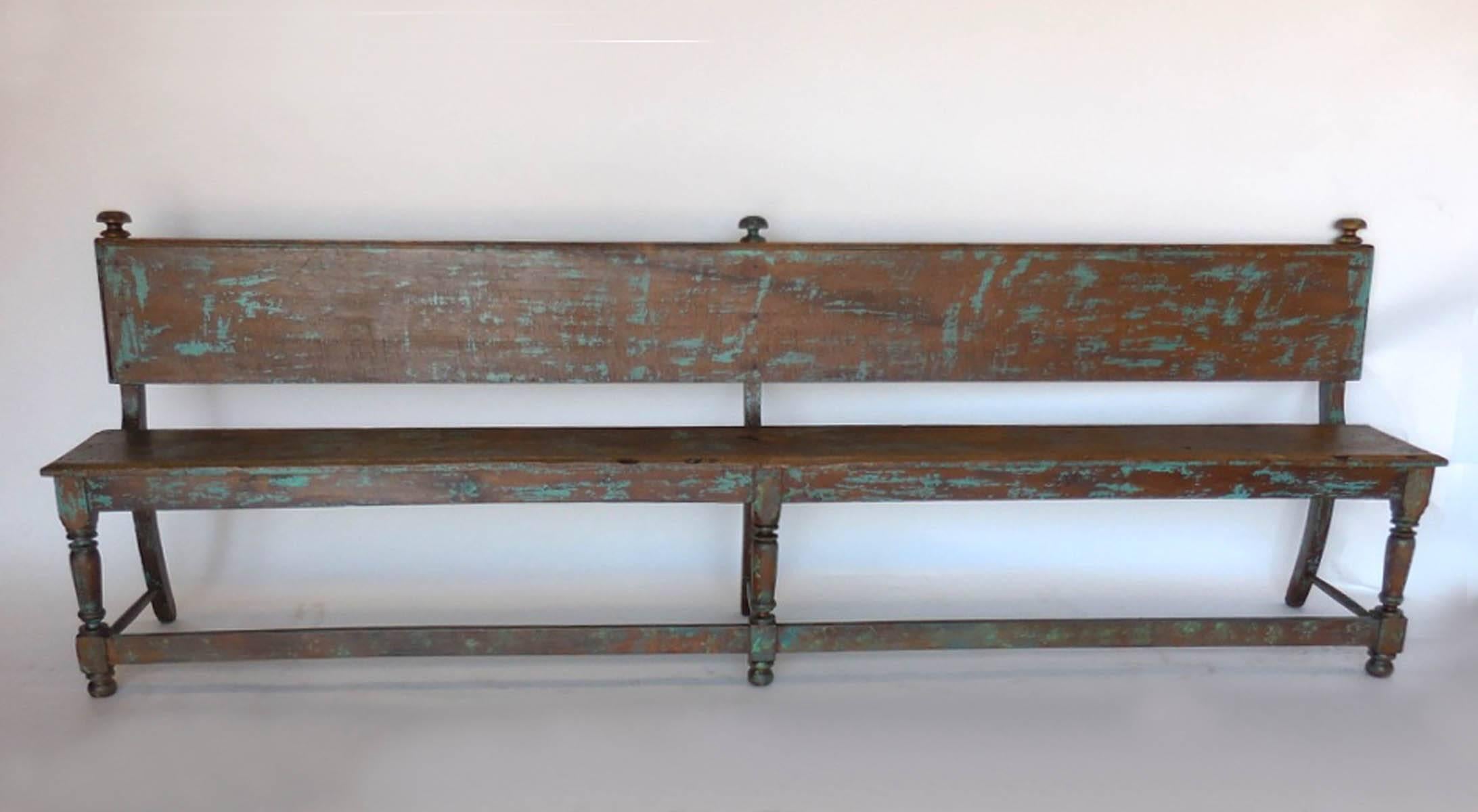 Graceful Spanish Colonial style bench with traces of old green paint. Front legs are turned, back legs are straight. Thin profile.