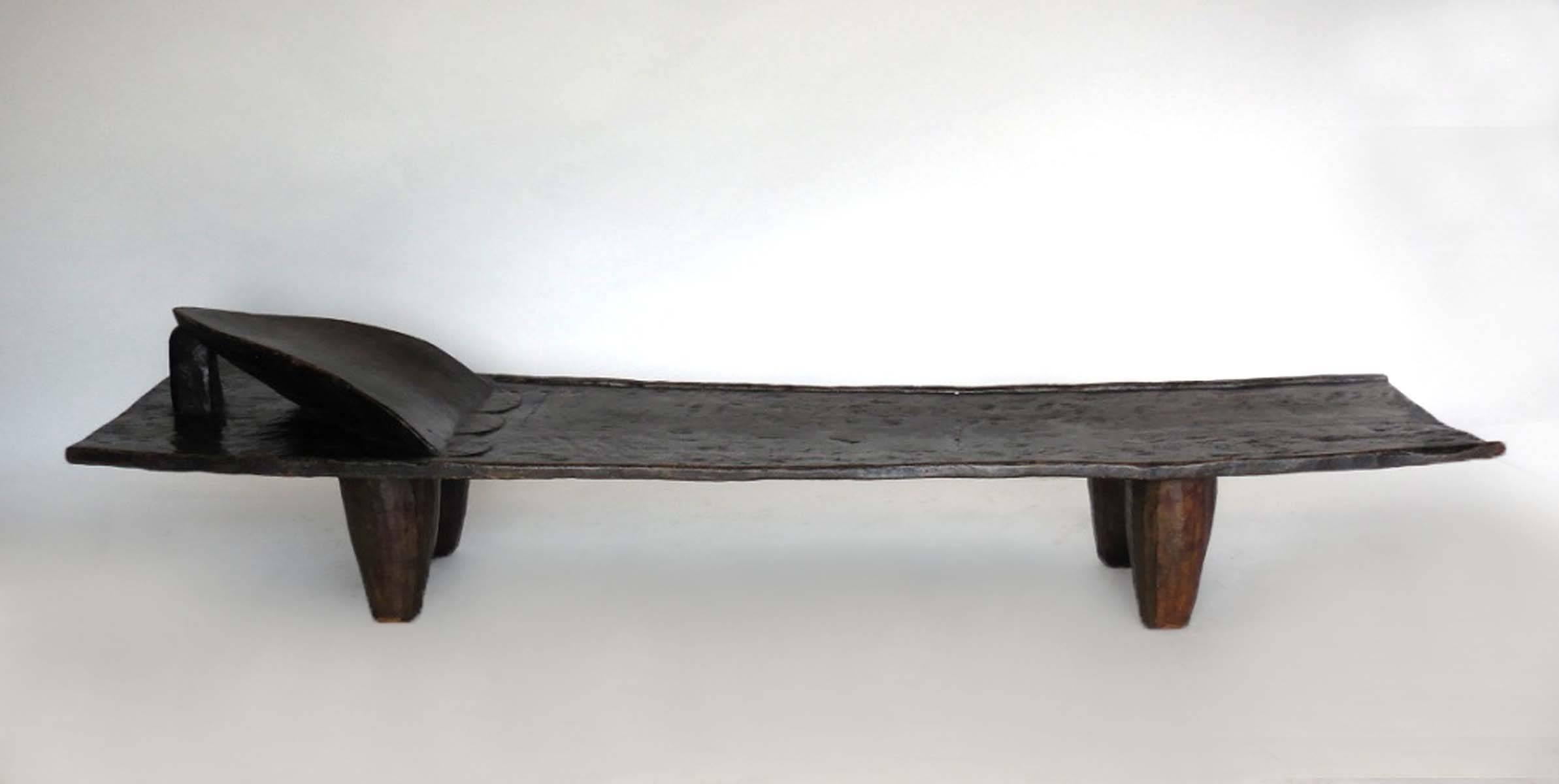 Antique wooden tribal bed carved out of one piece of wood. Conical legs, headrest and carved detail on top. Beautiful, worn wood, lovely dark patina. Senufo tribe, Mali.
Measures 21 to 23.5 inches deep and seat measures 12.5.