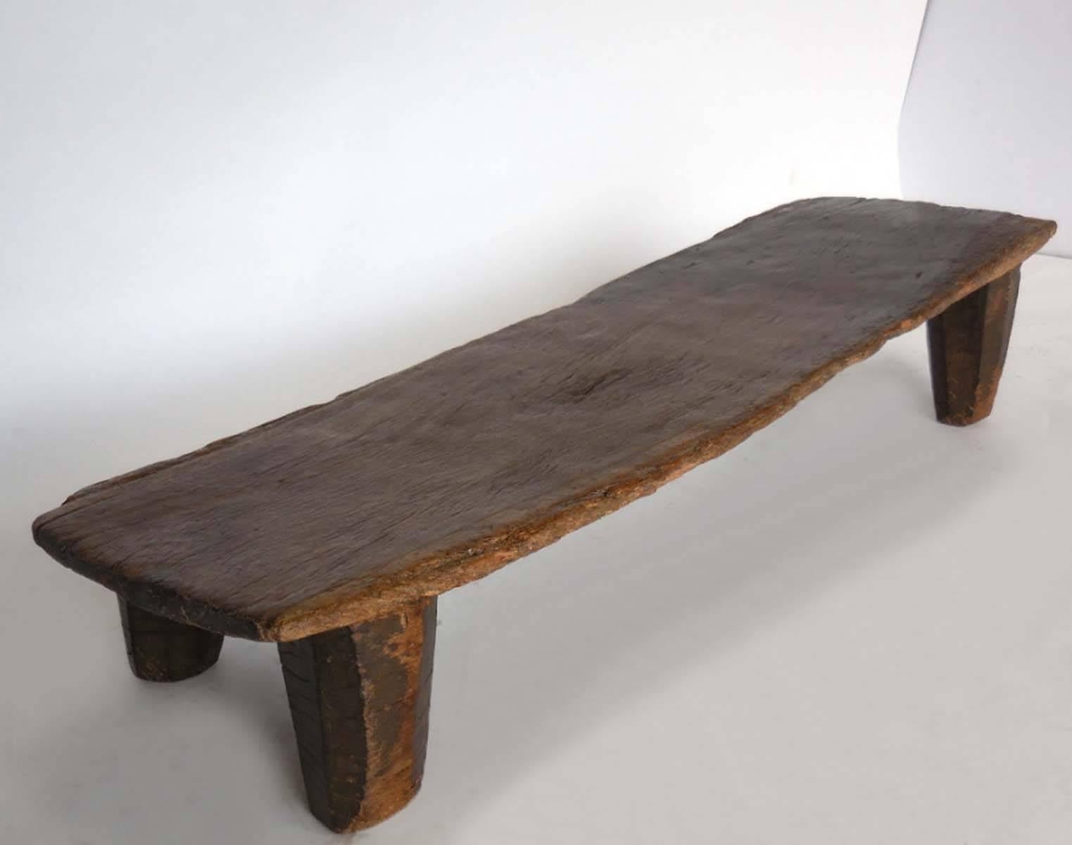 Carved out of one single piece of wood, this is a child's bed from the Nupe tribe in northern Nigeria.
Wonderful old patina throughout. Carved conical primitive legs. Swooping top from 8.5 inches to 11 inches tall. Great little coffee table, bench