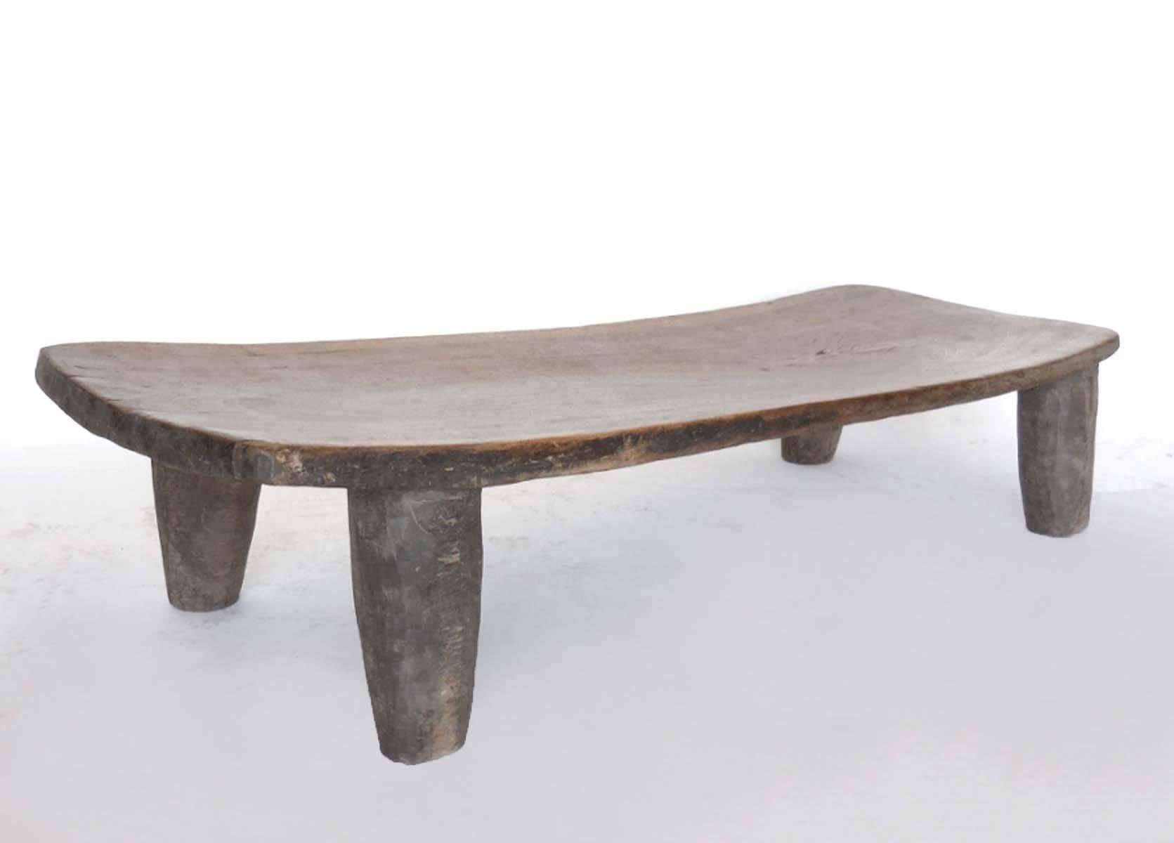 Carved from one piece of wood, this light colored early 20th century child's bed can be used as a petite coffee table or bench. The wooden top has lovely graining and patina and is one solid piece. Wear on the legs is commensurate with the age of