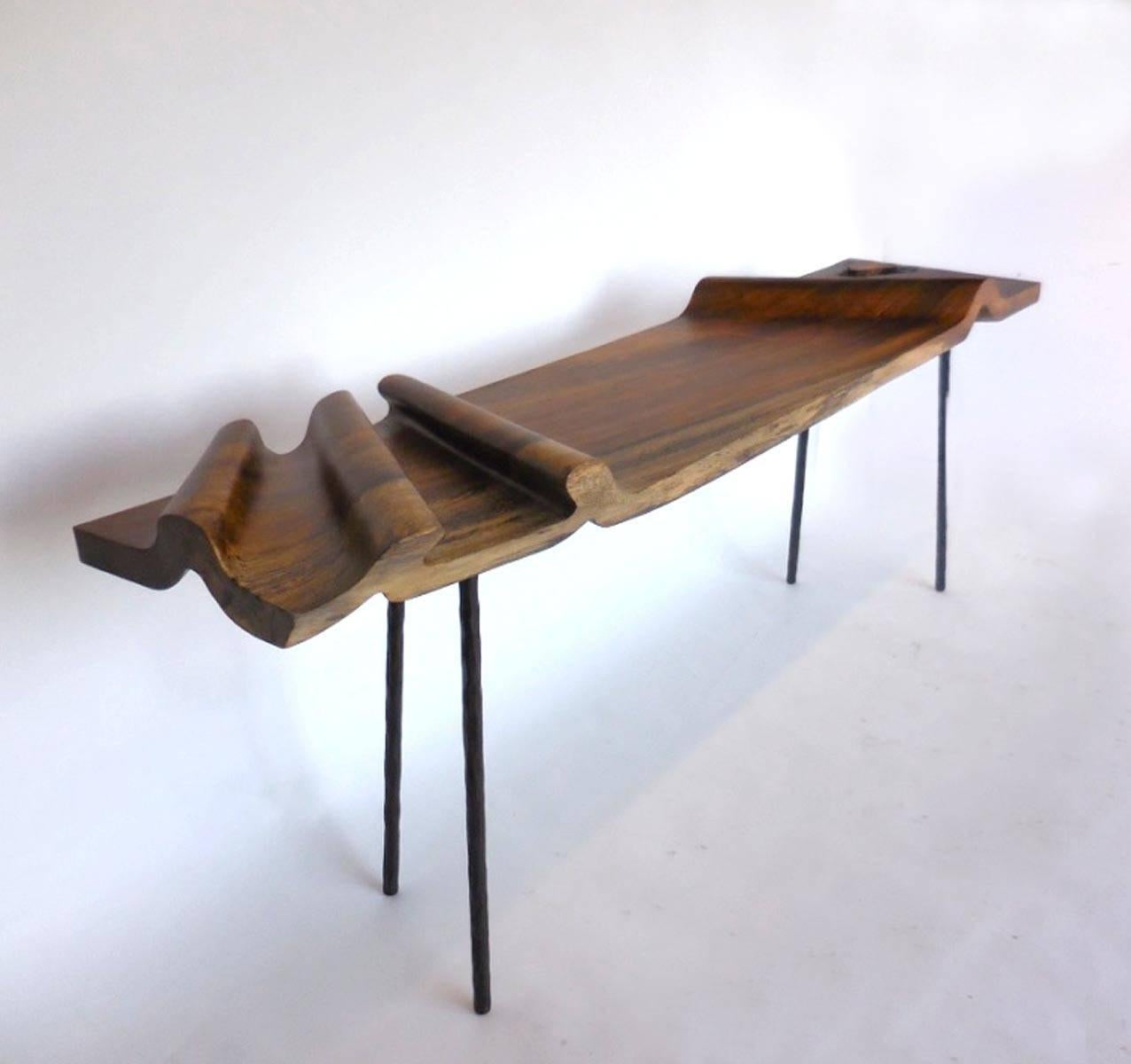 Top carved out of five inch thick topical conacaste wood, creating an undulating two inch top reminiscent of an unbolted roll of fabric.
Hand-forged custom iron legs. 