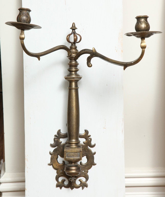 Very rare pair of late 17th century bronze swivel arm sconces with parapet finials over balustrade bodies, the two pairs of arms of differing heights and lengths, the backplates with pierced and embossed decoration.

English or Dutch East India