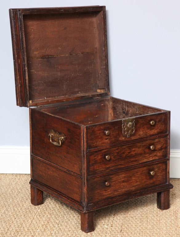 Rare 17th century English oak lift top chest in the form of a chest of drawers, the heavily molded top over three false drawers with 1/2 round molded dividers, over heavy molded base standing on original stile feet, and having original pierced brass