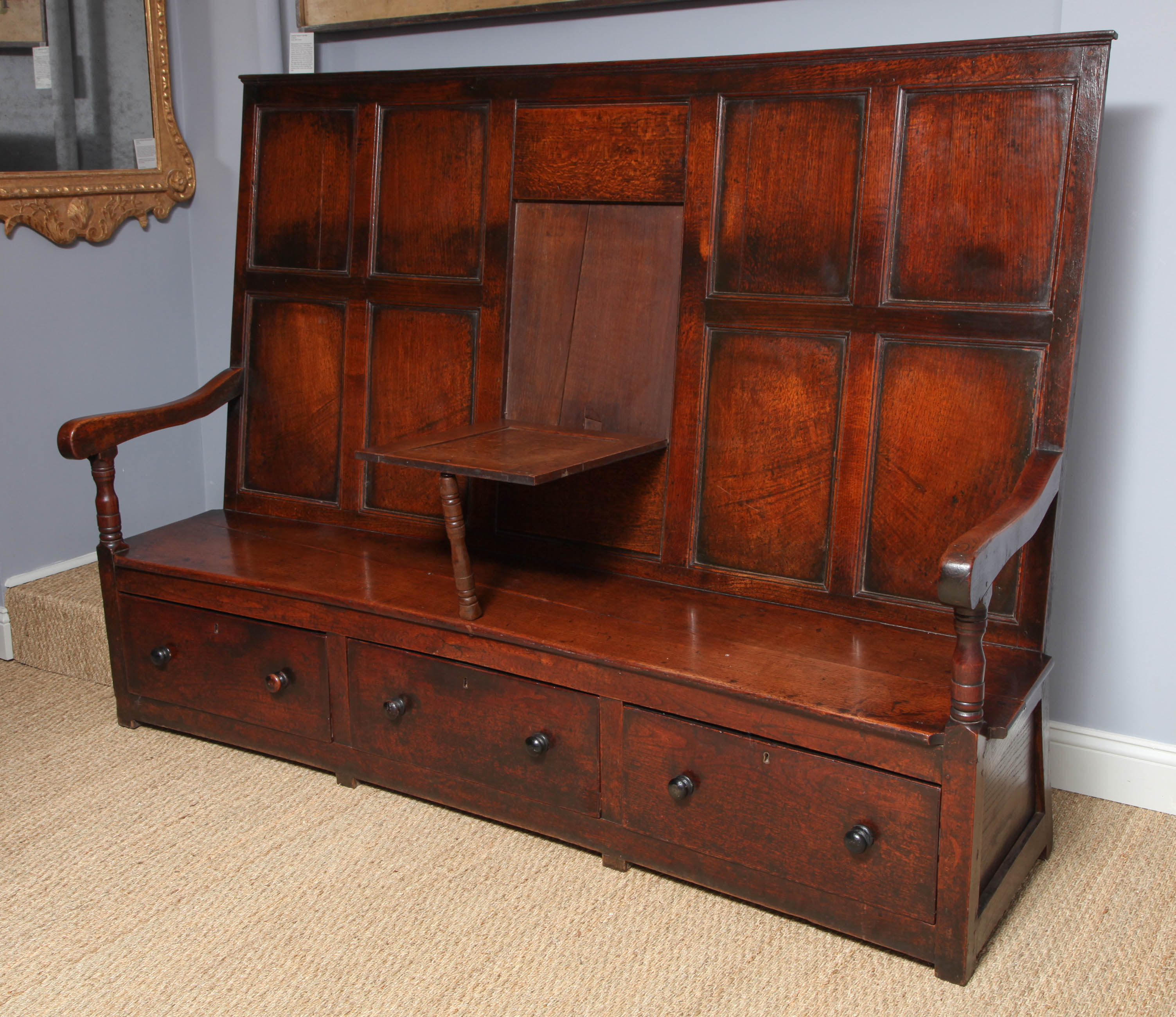 A very fine early 19th century English oak paneled barrel back settle with tuck away 