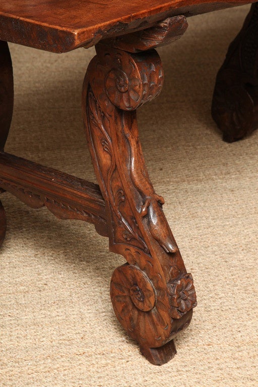 Remarkable Spanish 17th century walnut trestle table, the unusually thick two-inch single board top with vivid graining over profusely carved scrolled legs each with a raised salamander, variously carved with grape vines, tendrils, hanging fruit and