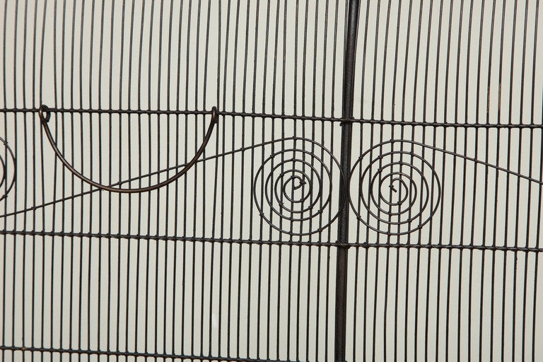 A rare American wirework firescreen with curved hooded form having classical double scroll decorative wirework elements and double hand-wrought handles, 19th century.