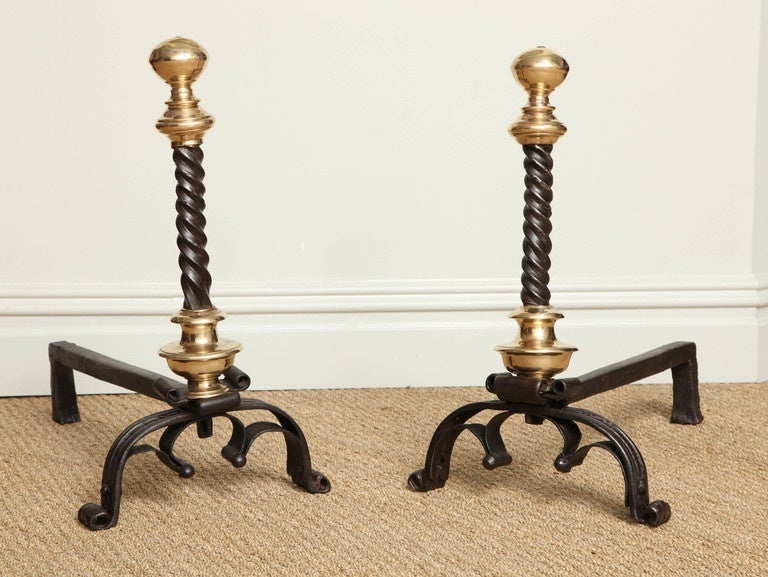 A fine pair of beautifully crafted 17th century andirons having suppressed ball finial and collar with twist shafts over an additional bronze collar standing on trefoil arched scrolled legs with wide banded ribbon details. Spanish, Netherlands,