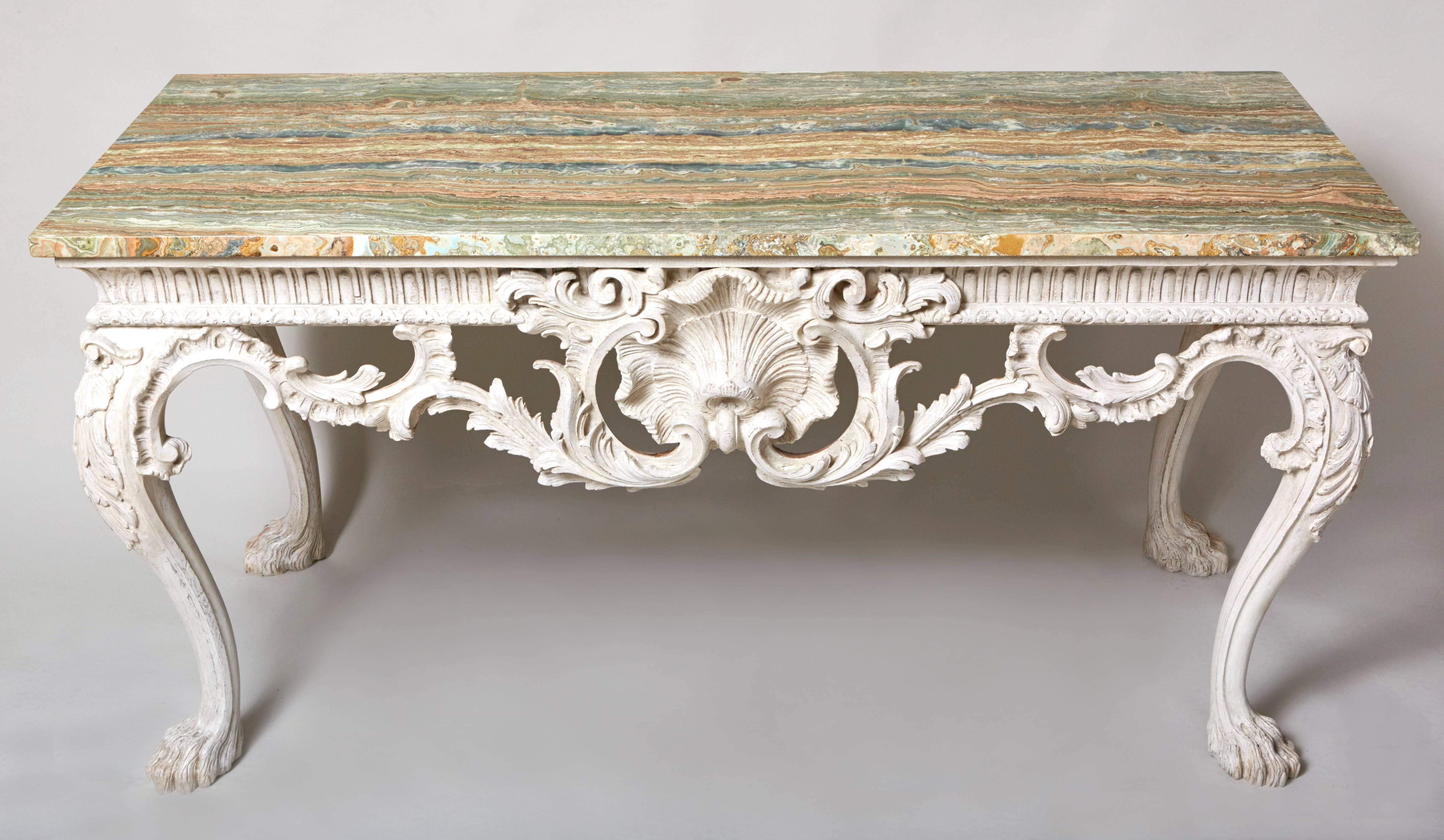 A 19th century George II style console table standing on hairy lion paw feet, the apron with bold Rococo carved scrolls and shell carved center in the manner of Matthias Lock. Stunning green veined onyx top.
    
    