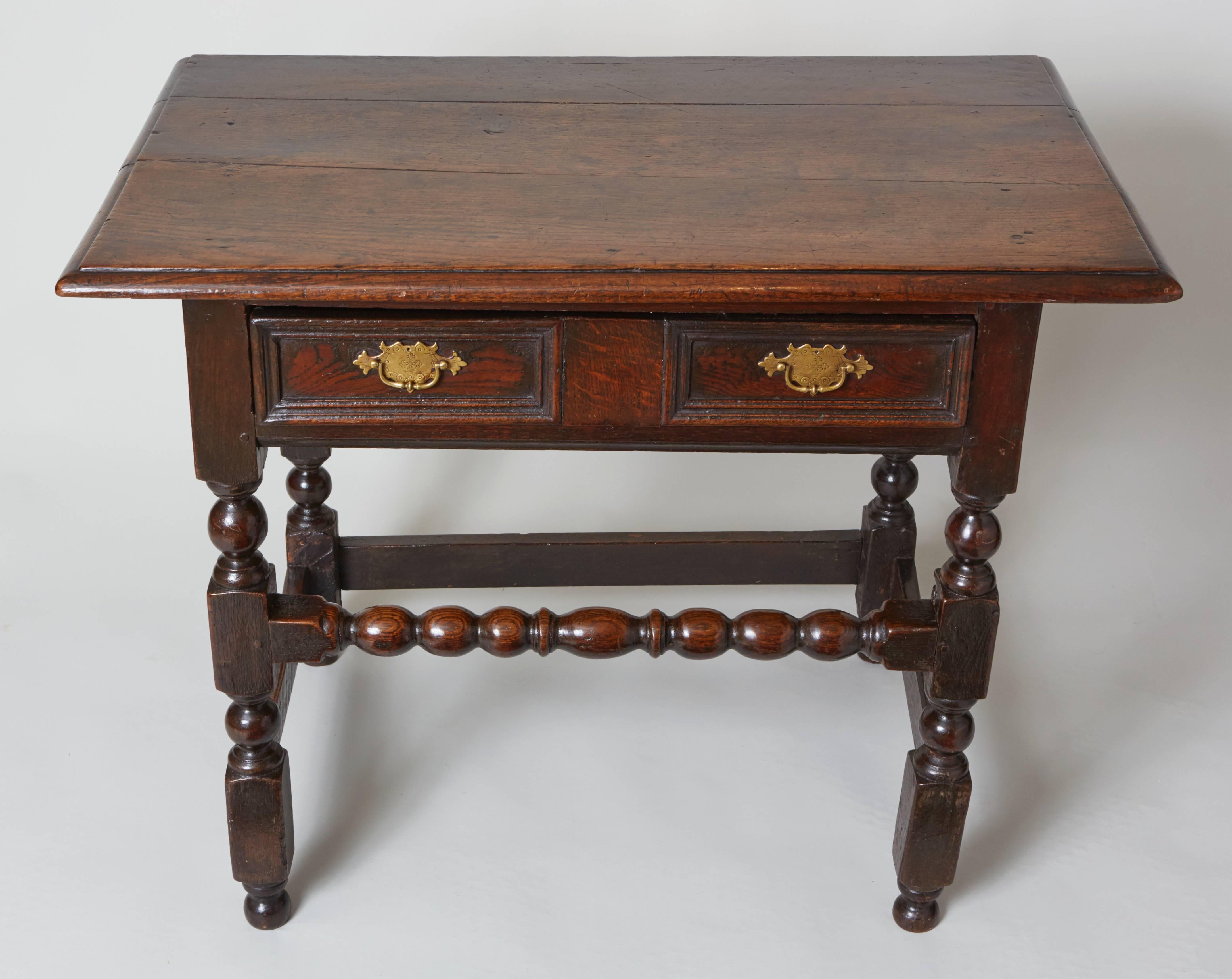 Lovely Charles II period English oak side table. The richly patinated oak top with heavy thumb molded edge over single drawer with double molded panels standing on block and ball turned legs the front with desirable bobbin and reel turned high