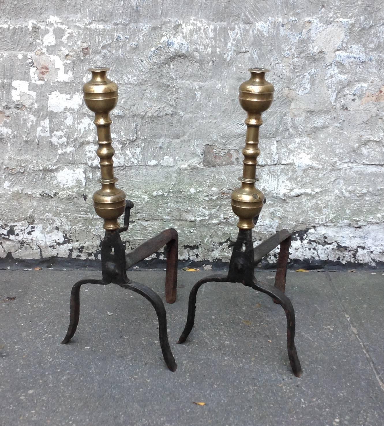 A pair of classical and elegant brass and wrought iron andirons with double acorn finials on balustrade shafts standing on graceful base of arched legs. Uncommonly shallow.