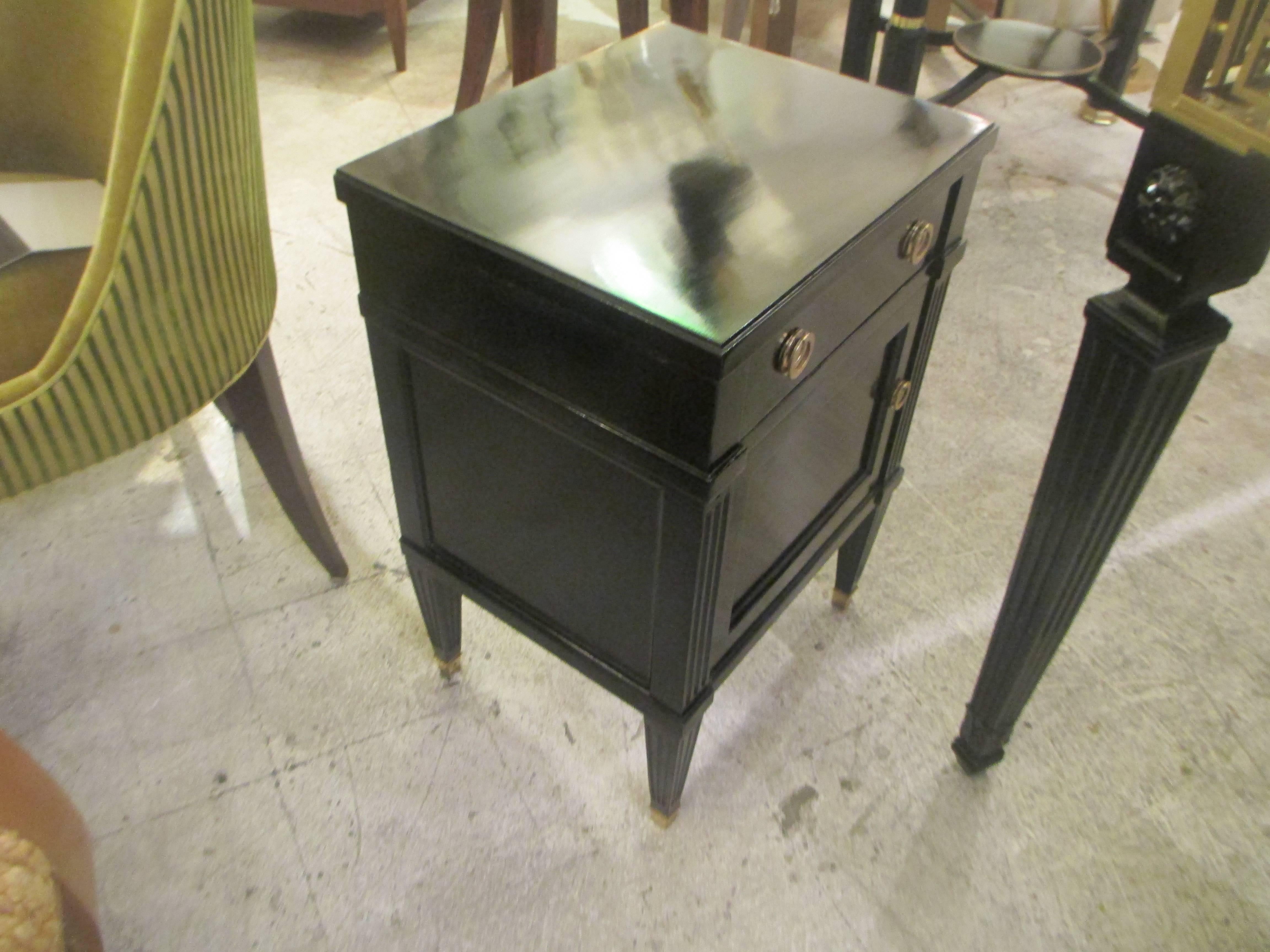 Pair of midcentury ebonized Louis XVI style nightstands with central drawer on tapered reeded legs.