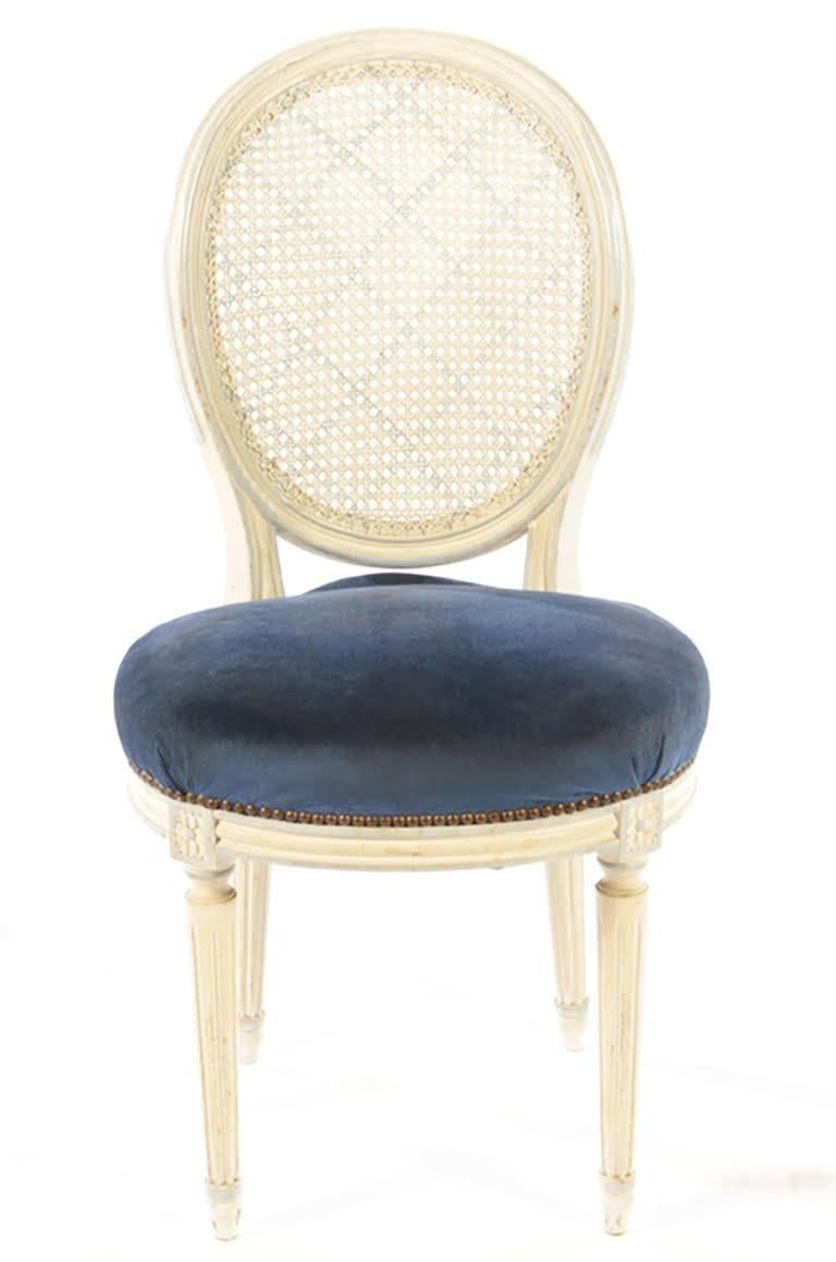 A set of eight painted balloon back dining chairs in the Louis XVI style with caned backs.
