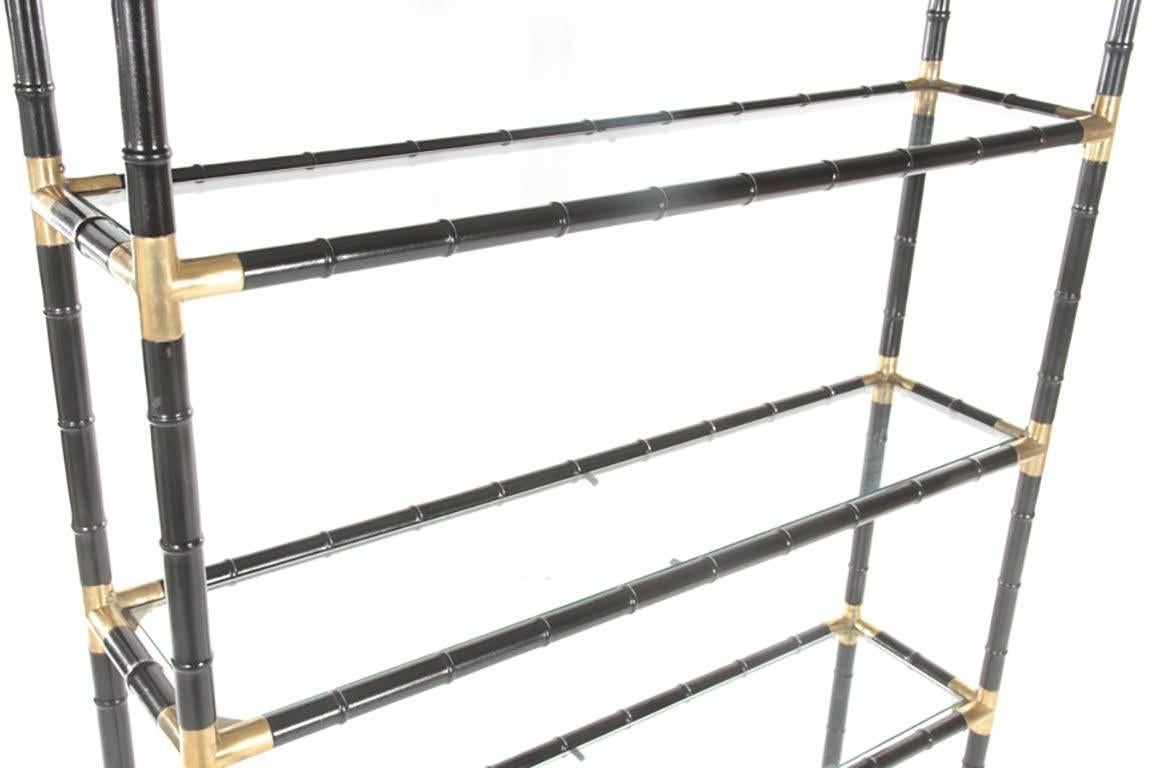 Ebonized faux-bamboo etagere/bookcase in the Billy Haines manner with four glass shelves and brass decoration.
