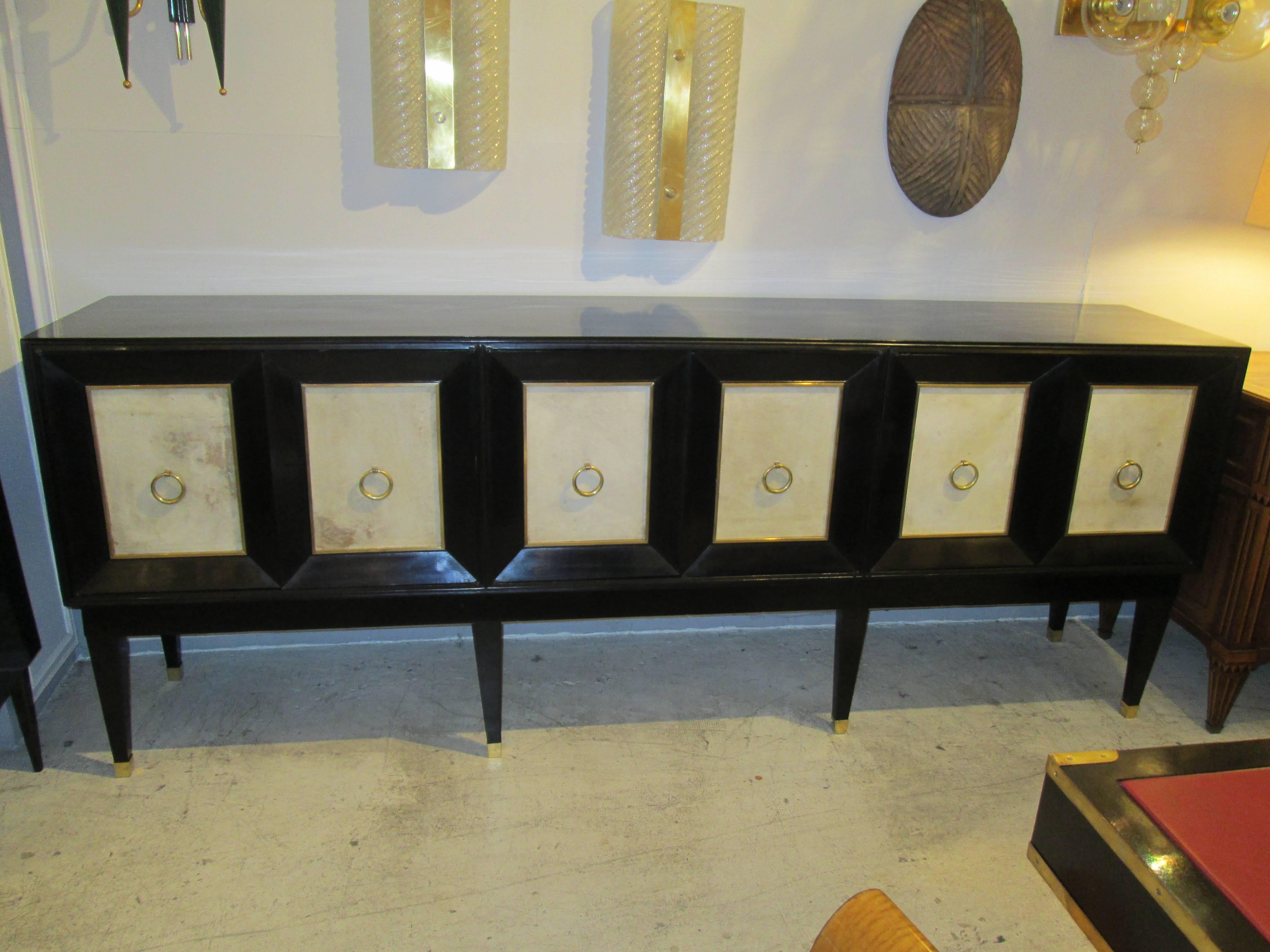 Ebonized sideboard with parchment doors and  brass banding on tapered legs ending in brass sabots. This sideboard measures 7 ft. 8 inches in length.