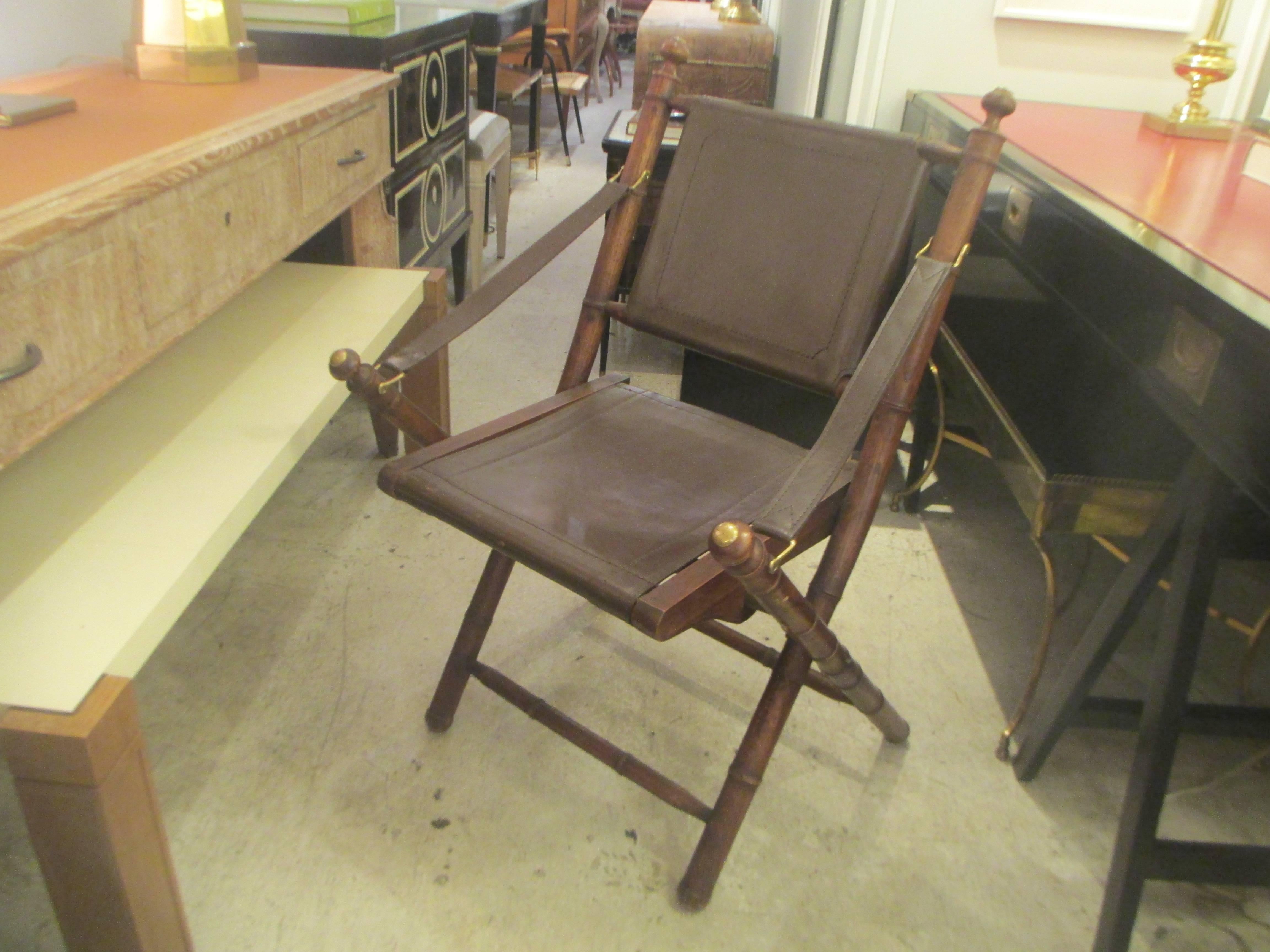 A very chic pair of hand-stitched leather and faux-bamboo campaign folding chairs with brass fittings.