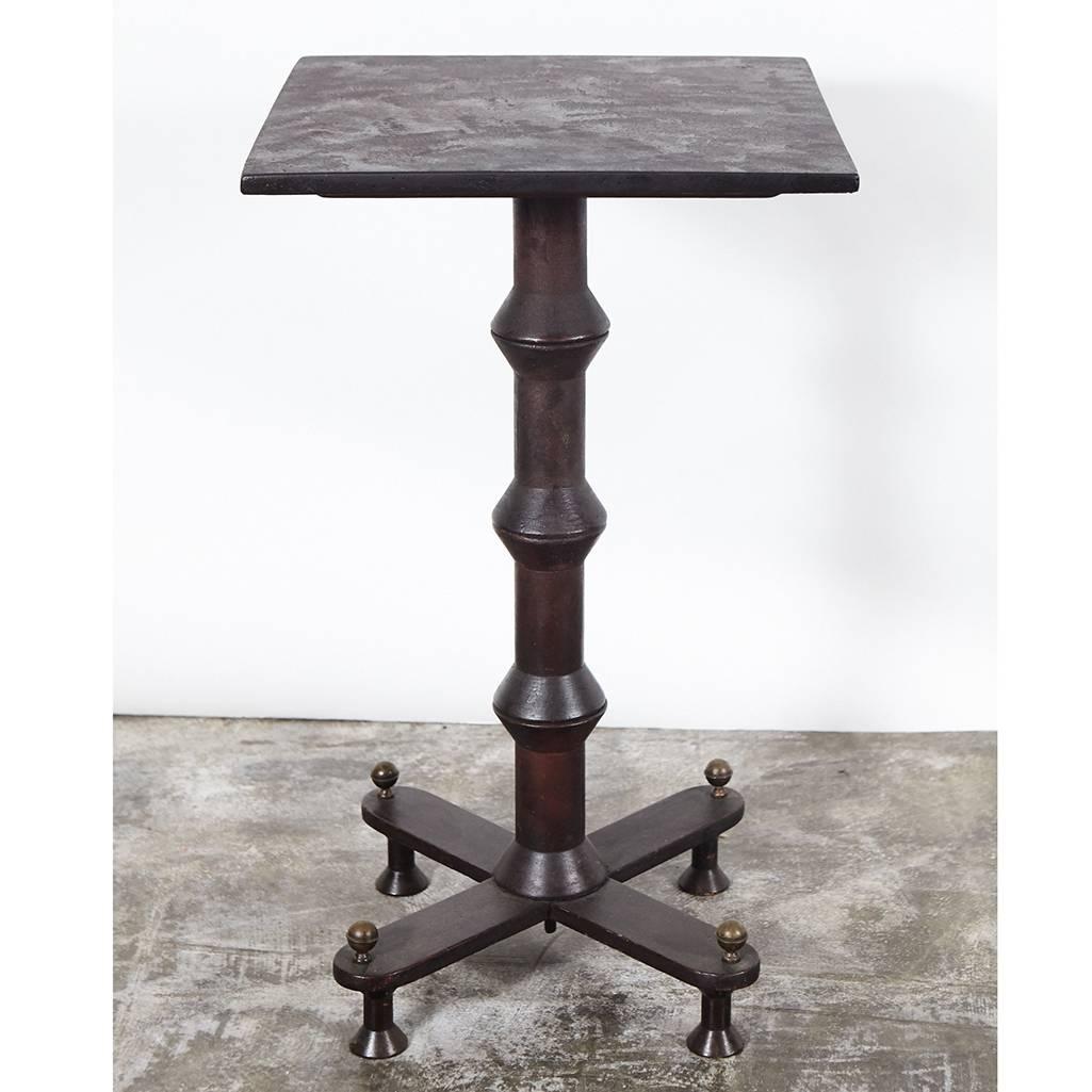 Spool furniture is an American style of furniture made during the turn of the last century from thread spools that were collected from textile factories. This spool table has a dark brown, rustic finish with one column of large spools and four spool