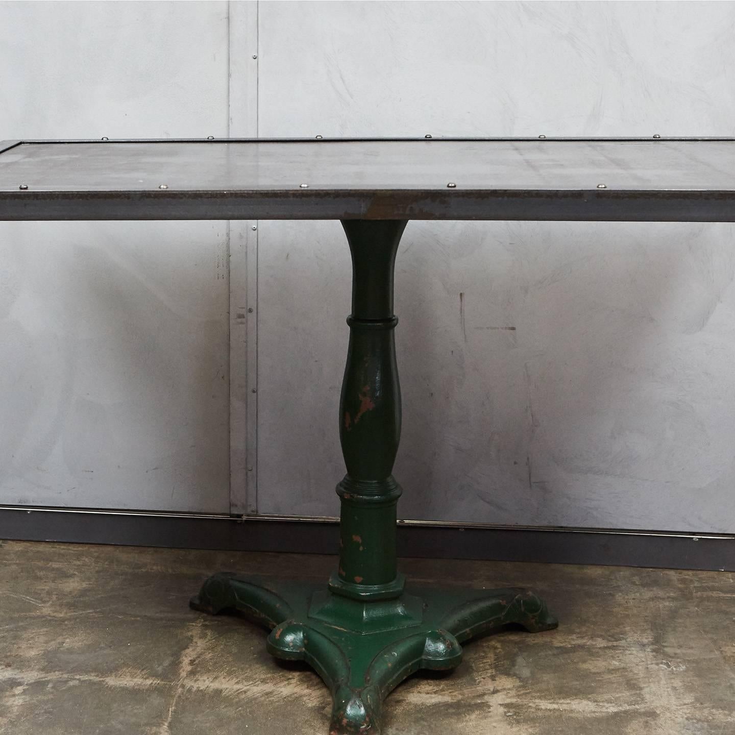 This piece has an antique painted metal base with beautiful details and a unique color. The base has been pared with a large metal top made in our workshop. This table combines the old and the newly crafted for a one of a kind piece suited to a