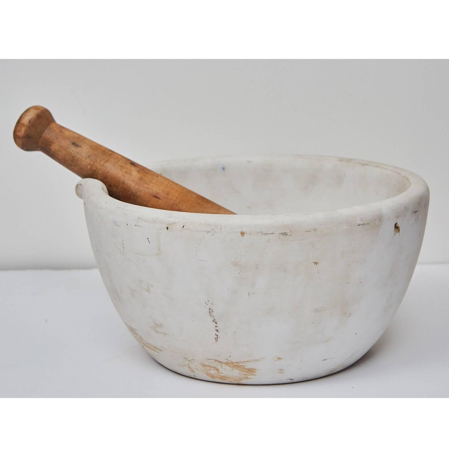 This large mortar and pestle is made from white stone with a nice lip on the mortar and shaped wooden handle on the pestle. We believe this piece was used in an early 20th century pharmacy as it shows nice signs of age and wear.
 